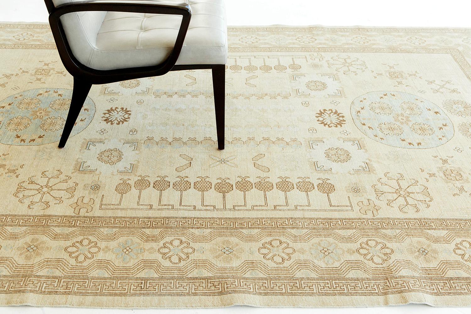 A sophisticated revival rug in the Khotan style, with various tribes' designs and geomoteric patterns that stand out due to the hand-knotted texture. The rug is elegantly accentuated by the addition of Dutch white and a variation of brown termed