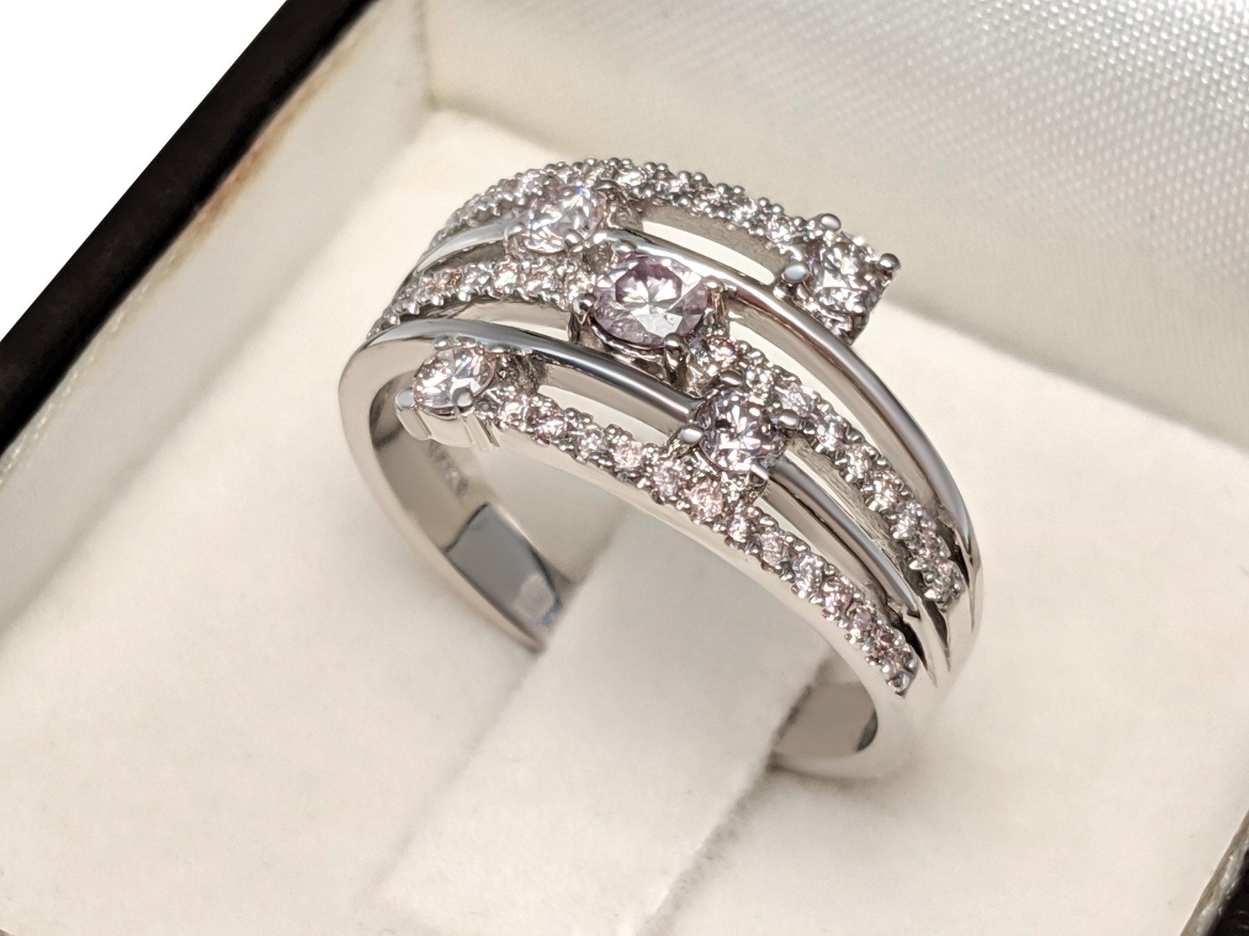 This exquisite ring features 0.80 carats of natural colored light pink and fancy light pink diamonds, beautifully arranged in a 14 kt white gold setting. The delicate pink hues of the 49 diamonds are perfectly complemented by the warm, romantic glow