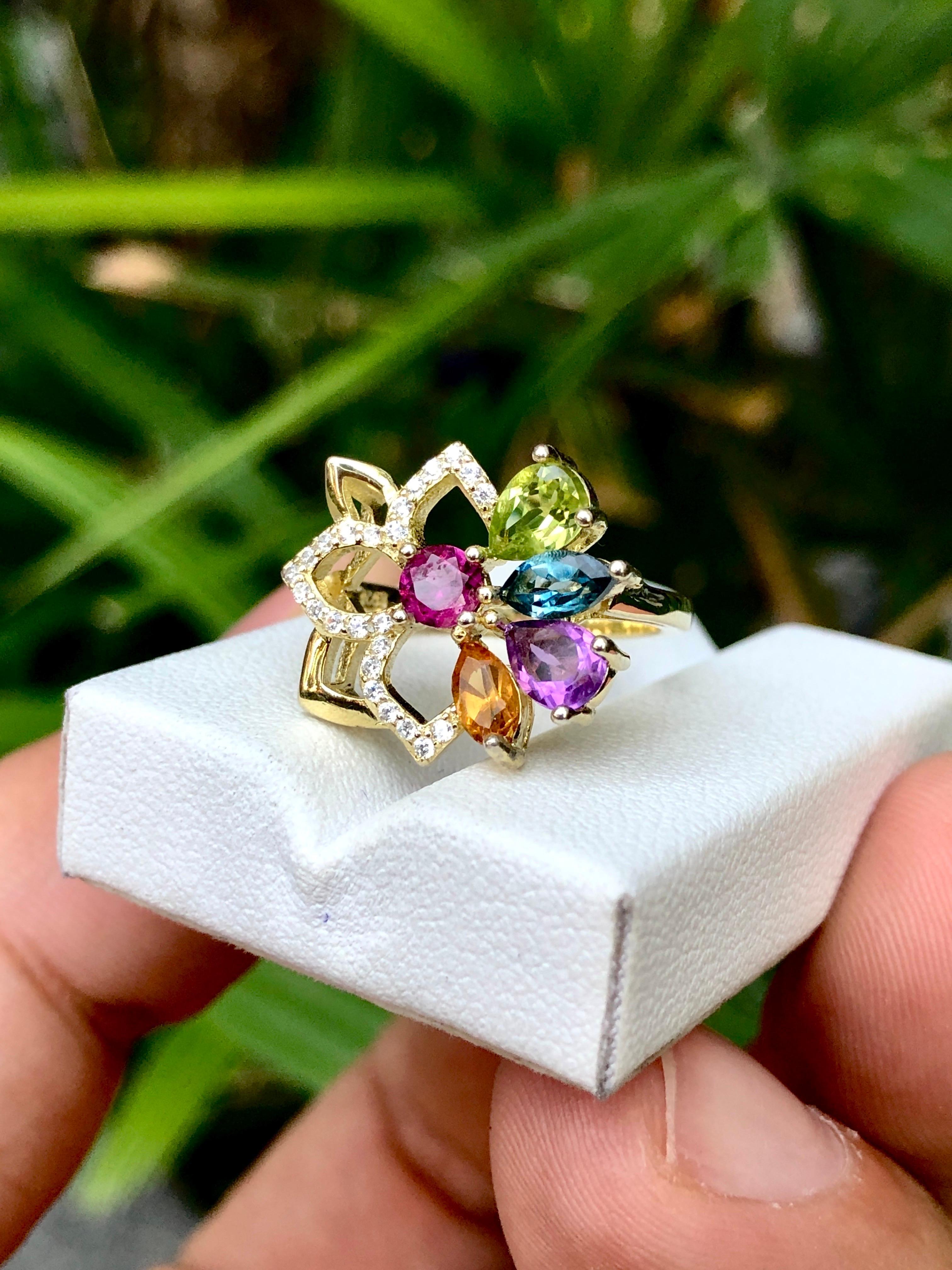 A stunning 925 silver ring adorned with exquisite citrine, London blue topaz, amethyst, and peridot gemstones, culminating in a regal crown of sparkling cubic zirconia. Elevate your style with this enchanting piece that captures the essence of