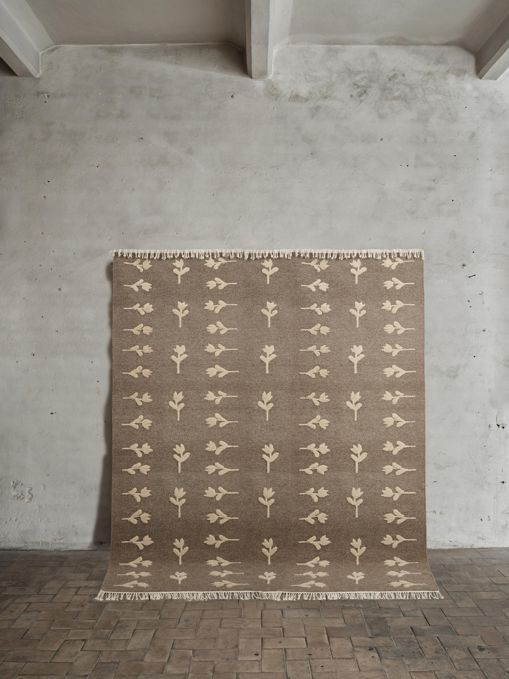 No.18 Rug by Cappelen Dimyr
Dimensions: D 230 x H 280 cm (excl. fringes)
Materials: 85% wool, 15% cotton

Colonnade no.09 & Rug no.18 is a grey-brown flat-woven rug with light beige hand-knotted floral pattern which gives a slightly high-and low