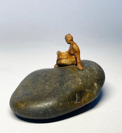 "Woman Reading on Smooth Rock" miniature bronze figure on smooth river rock