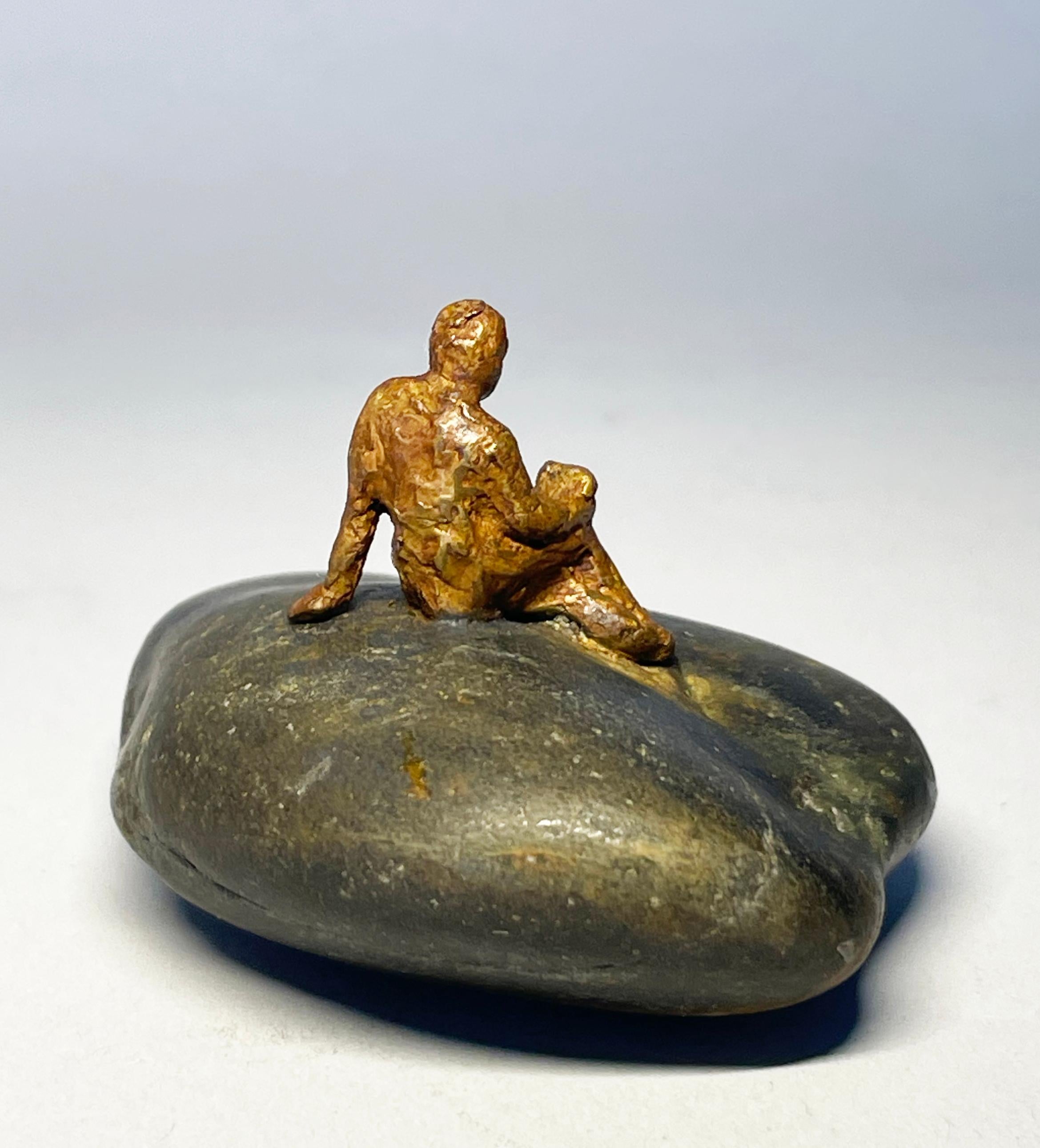 Una mujer de bronce en miniatura está leyendo. ¡Encontró la roca perfecta para asentarse! Éste es el número 4 de una edición de 12, pero cada número de edición varía ligeramente debido a la roca encontrada única que el artista ha seleccionado para