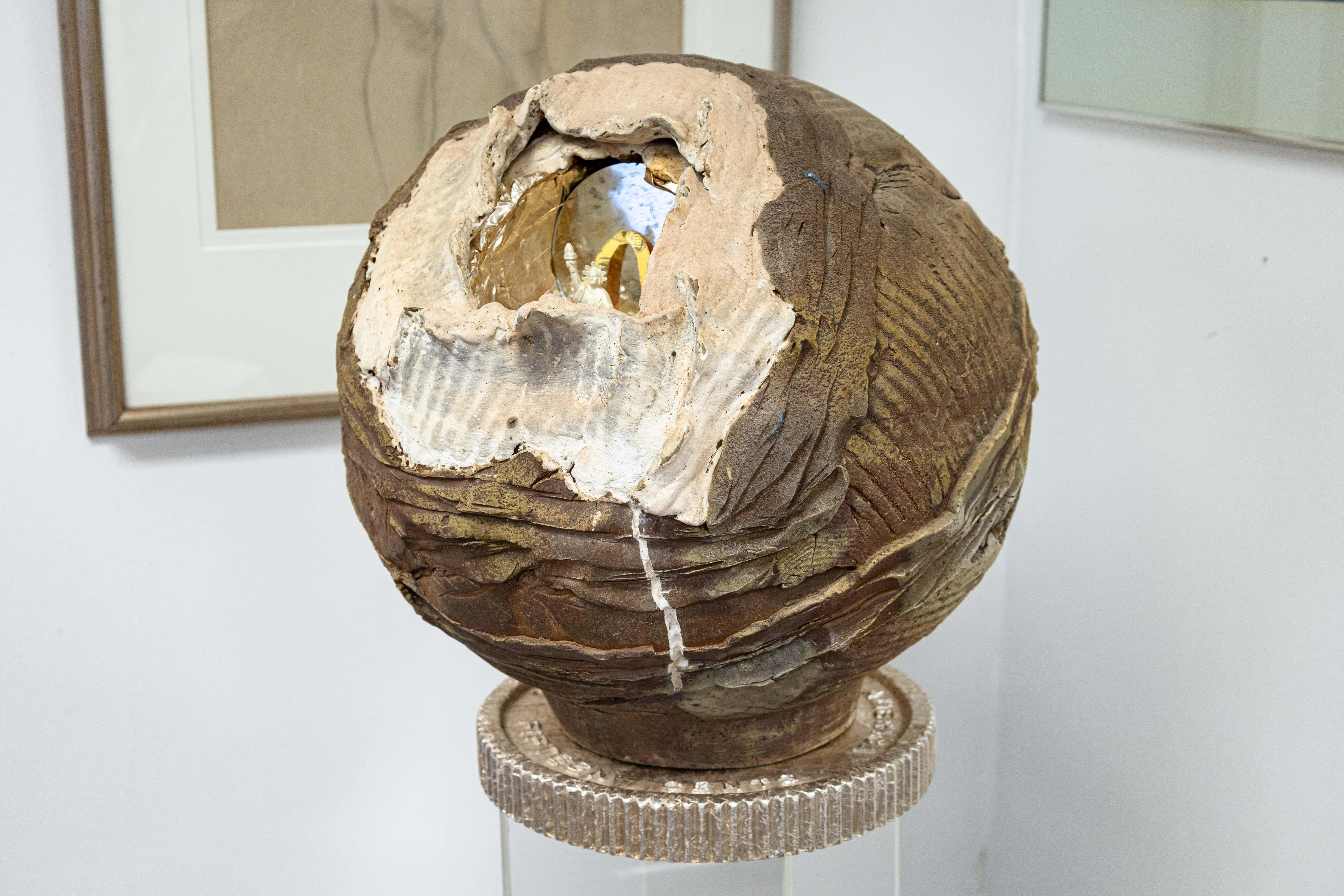 Une sculpture conceptuelle contemporaine qui est une célébration satirique des McDonald's par l'artiste du Michigan Noah Alonso. Vers 1990. Une boîte à emporter dorée devient la base d'un piédestal sur lequel est suspendu un globe en céramique en
