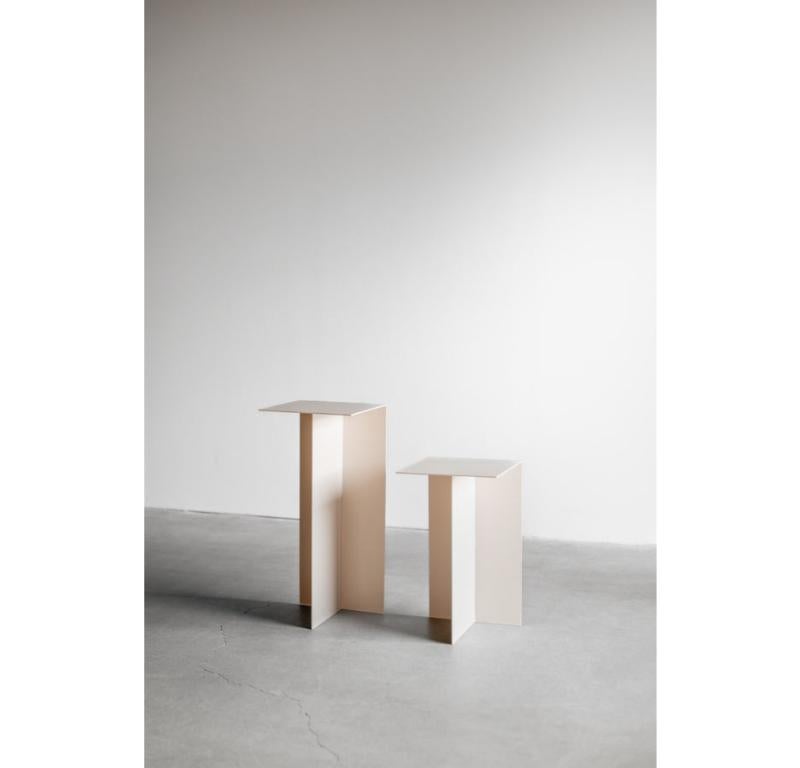 El pedestal Noah es una discreta mesa de centro que combina a la perfección un diseño minimalista con un tono cálido y neutro. Fabricada en acero industrial, su sencilla forma geométrica se realza con un acabado marfil de tonos suaves, creando una