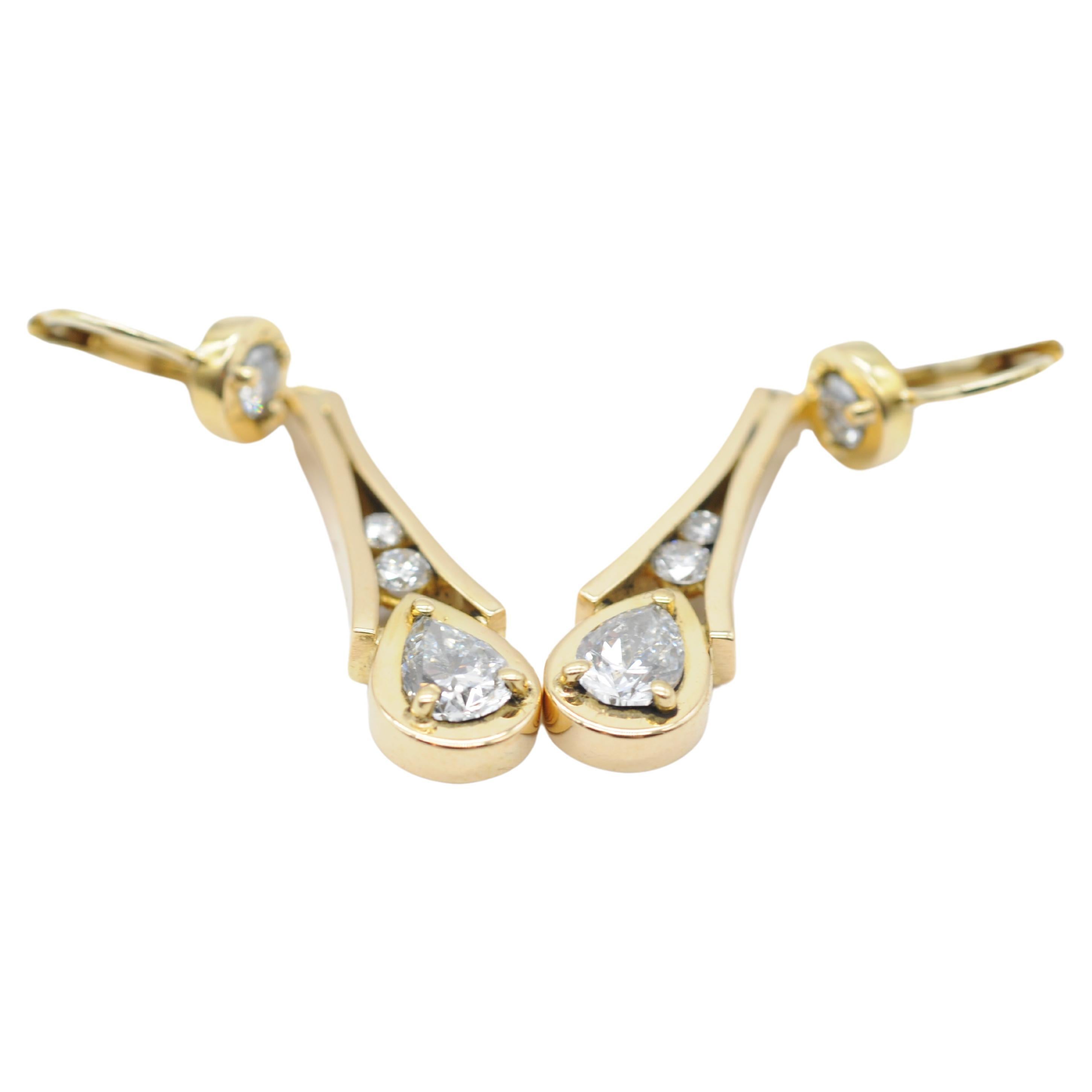 
Introducing a pair of exquisite 18k yellow gold drop earrings adorned with stunning diamonds in brilliant and pear cuts. Each earring features a captivating arrangement of diamonds, with three brilliant-cut diamonds adorning each piece, ranging in