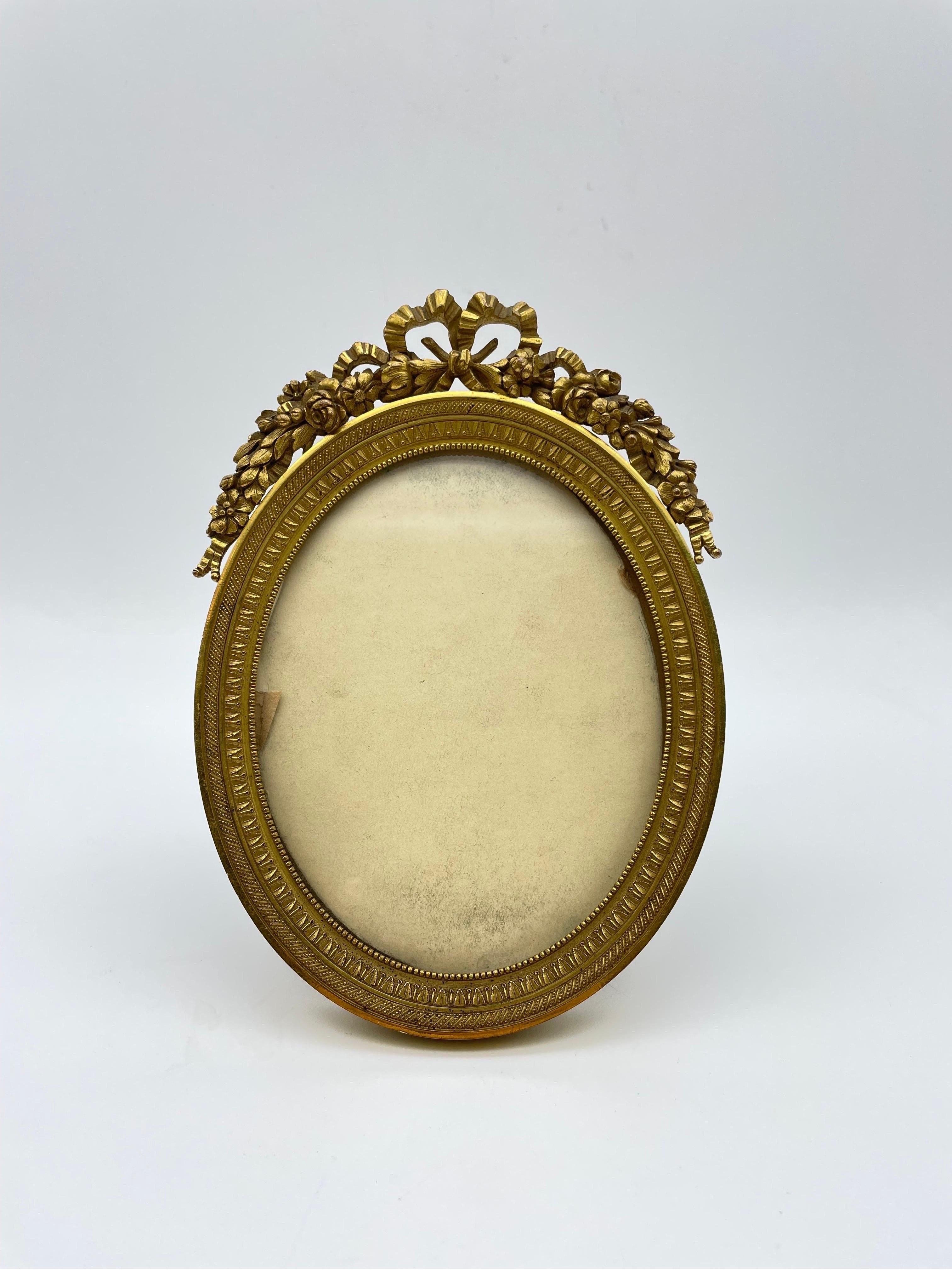Neoclassical picture frame made of solid bronze with extremely fine engraving and gilding. Oval body with neoclassical floral crowning and a so-called Louis XVI loop.
Extremely fine and high-quality workmanship.

A stand and an eyelet are attached