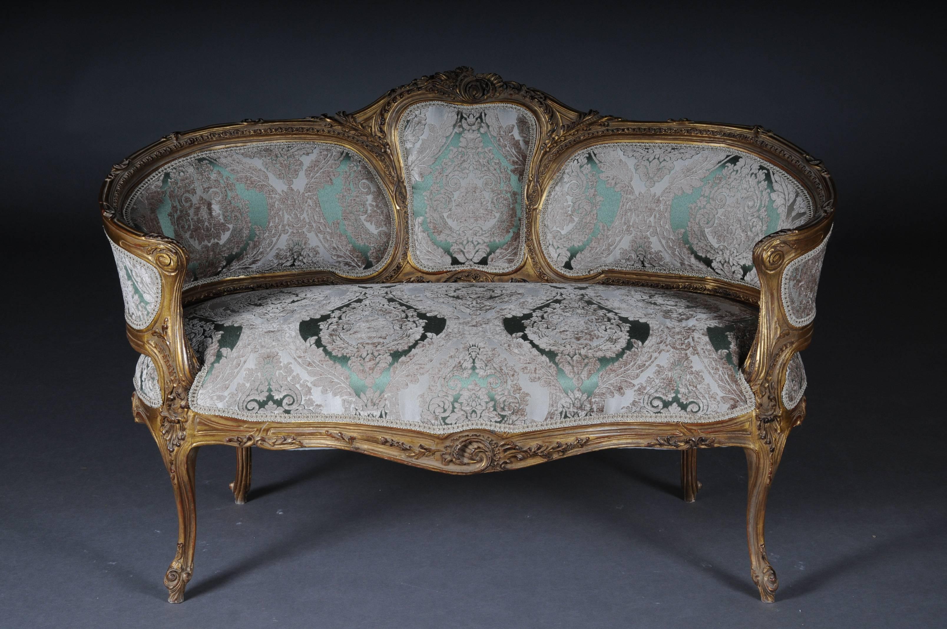 Solid beechwood, carved and gilt gilded. Semicircular rising, curved backrest framing with rocaille crowning. Appropriately curved frame with rich carved ornaments. Also decorated frame on curved legs. Seat and backrest are finished with a