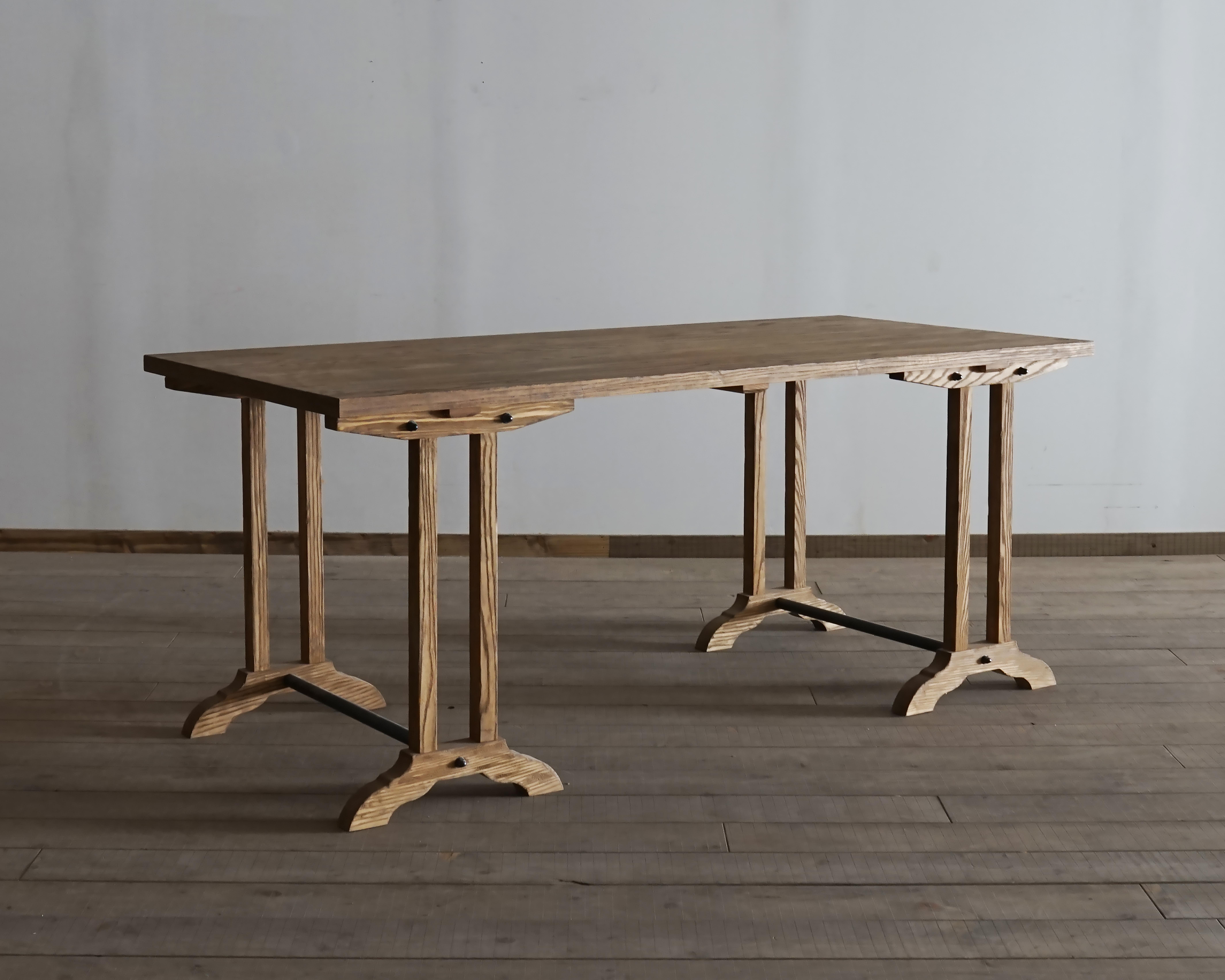 This trestle table is based on a French workbench and has been made in the style of an antique. The simple straight lines of the top and the eight legs give the table a different appearance depending on the angle of view. The only curve is at the