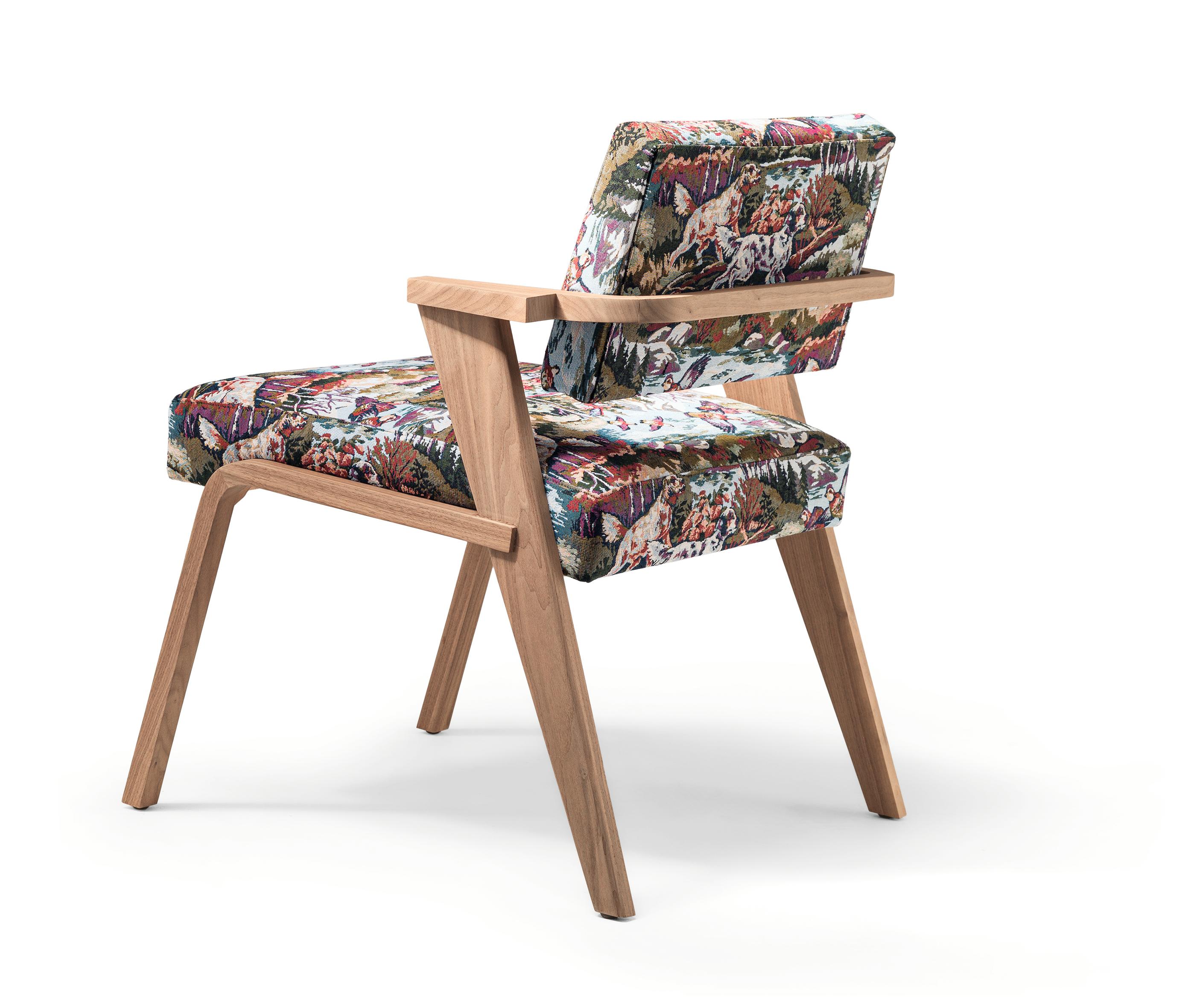 NOCINA/D is a dining armchair completely made from solid Canaletto walnut wood, then finished in matt natural (2% gloss). The seat and the backrest are covered with a fabric depicting a hunting scene.