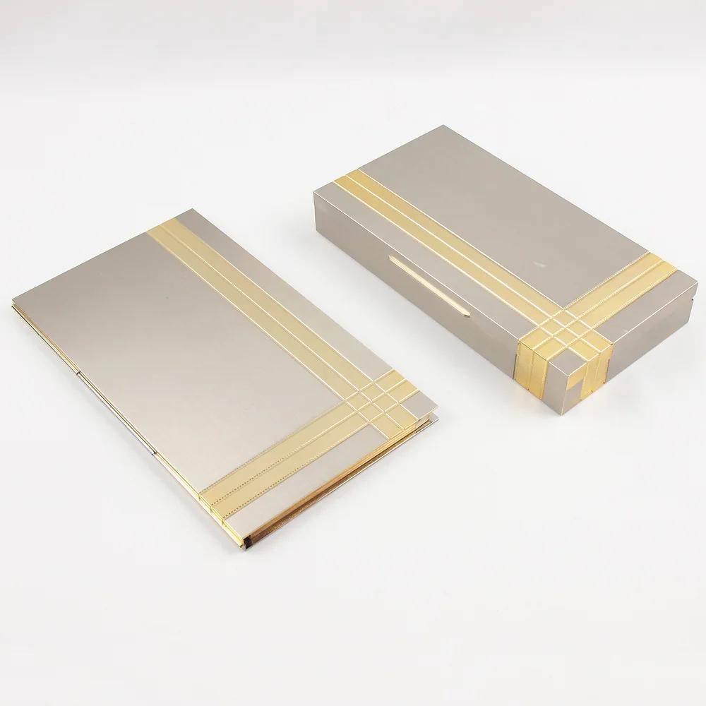 Italian designer Noel BC Italy designed this modernist desk accessory set in the 1970s. The set is built with a rectangular box and a contact book. The pieces boast a geometric shape with chrome and gilt brass design in silver and gold colors. The