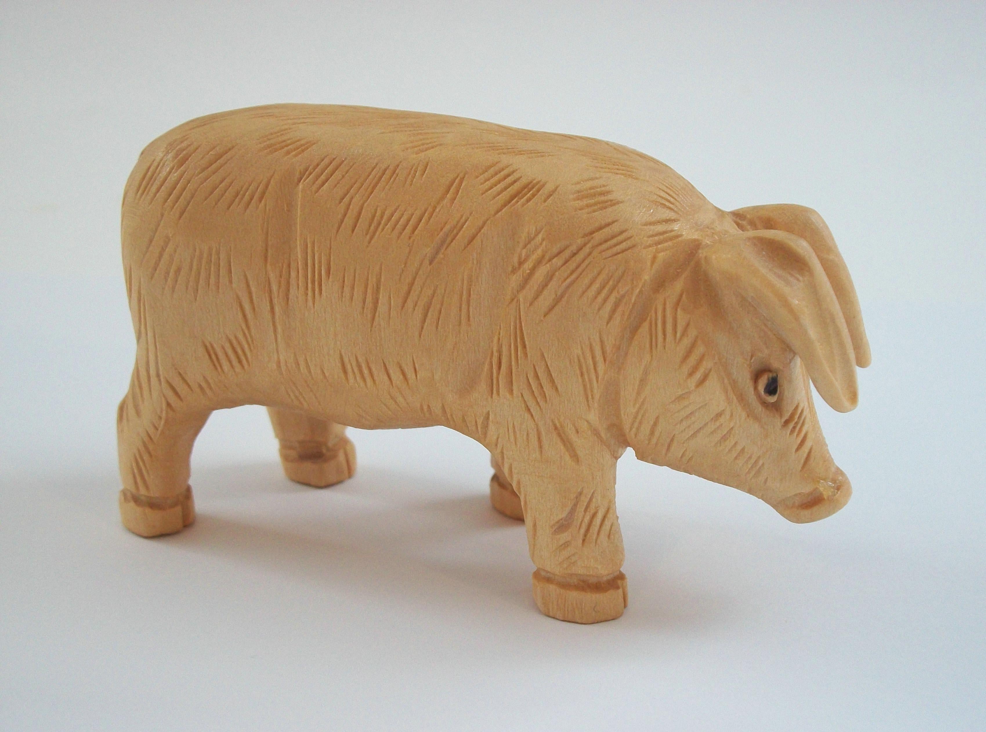 ATELIER NOËL GUAY - Vintage pine sculpture of a pig - featuring a well modelled form with an intricately chiseled coat, large drooping ears and closely cropped tail - unvarnished finish - signed on the belly - Canada (Quebec) - late 20th