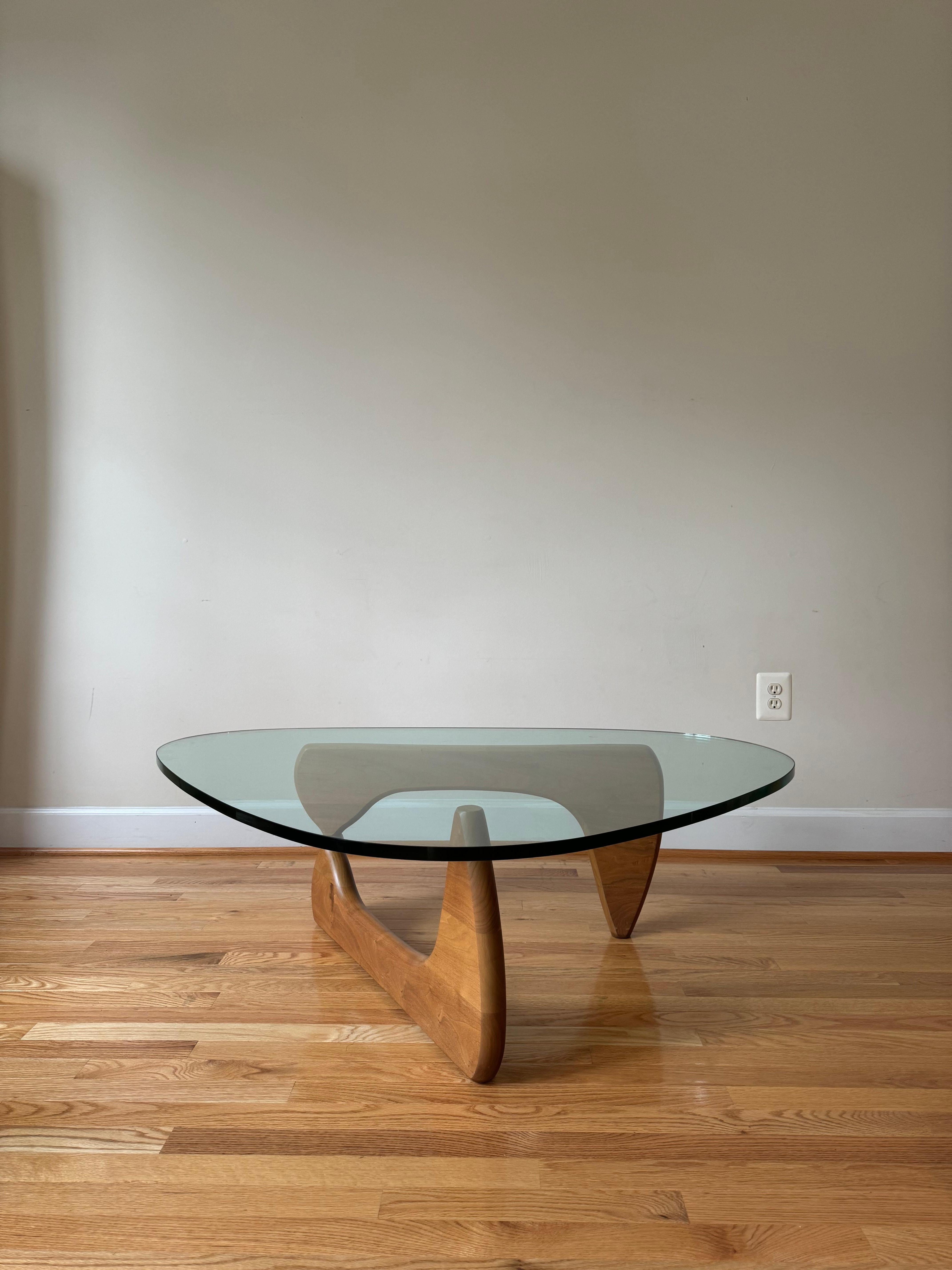 This classic table authorized by the Isamu Noguchi Foundation was originally created in 1944. The brilliantly simple design consists of only three elements, the glass top and two interlocking wood base pieces. The table is an extraordinary harmony