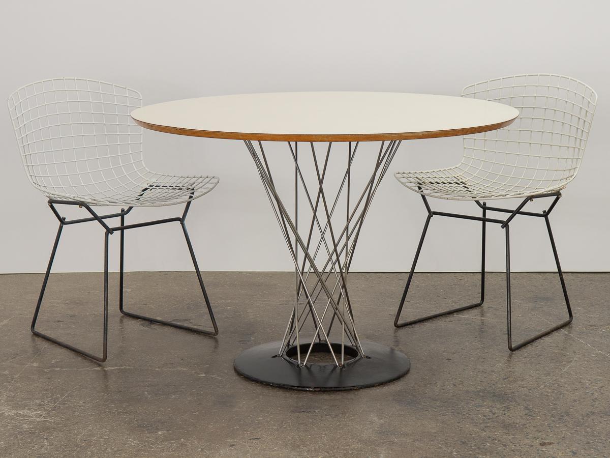 Early Cyclone dining table, designed by Isamu Noguchi for Knoll. A classic organic modern design by the renowned sculptor and designer. Sculptural chrome steel wire base set in circular cast iron foot. In overall good condition, with clean white