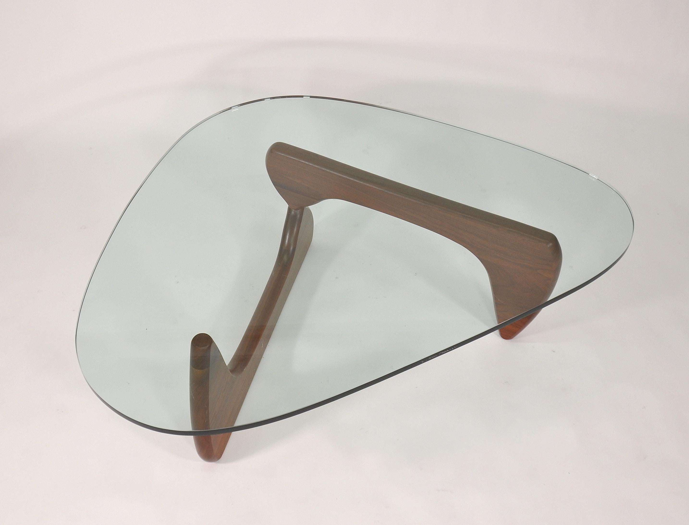 A vintage example of the iconic Mid-Century Modern IN-50 walnut and glass cocktail table designed by Isamu Noguchi in 1944, manufactured by Herman Miller. Integrates well with virtually any decor, from Danish or Scandinavian Modern interiors to