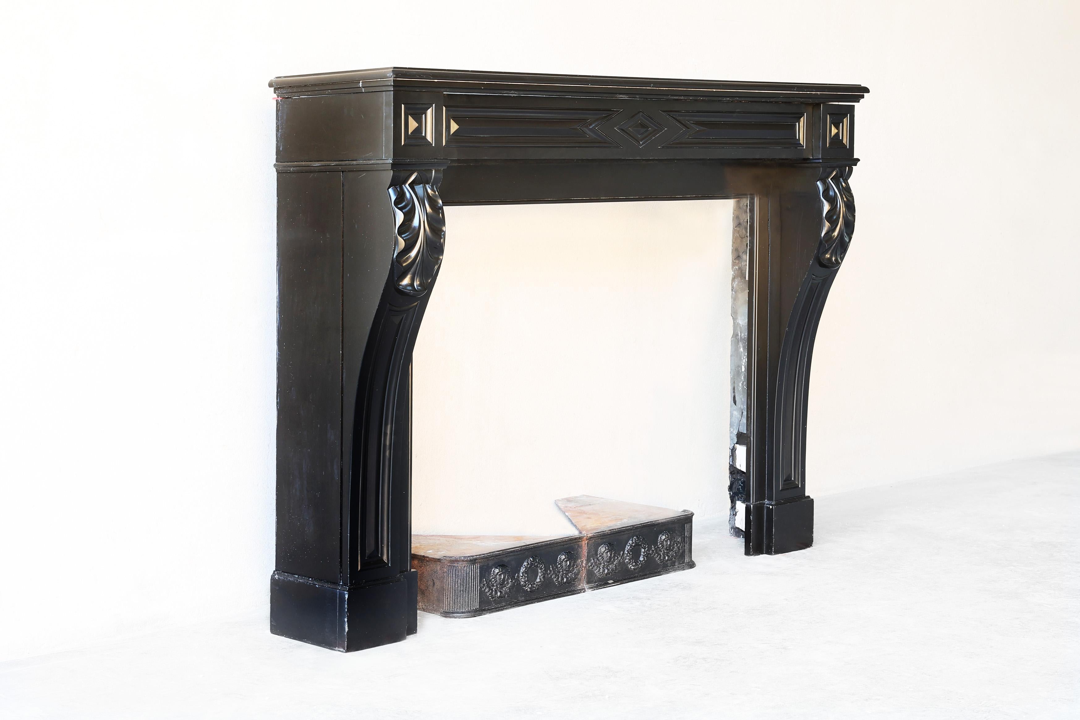 Beautiful Noir de Mazy marble fireplace from the 19th century in the style of Louis XVI. This antique fireplace has a straight top and slightly curved legs. The fireplace has beautiful ornaments and decorations and fits into many interiors.