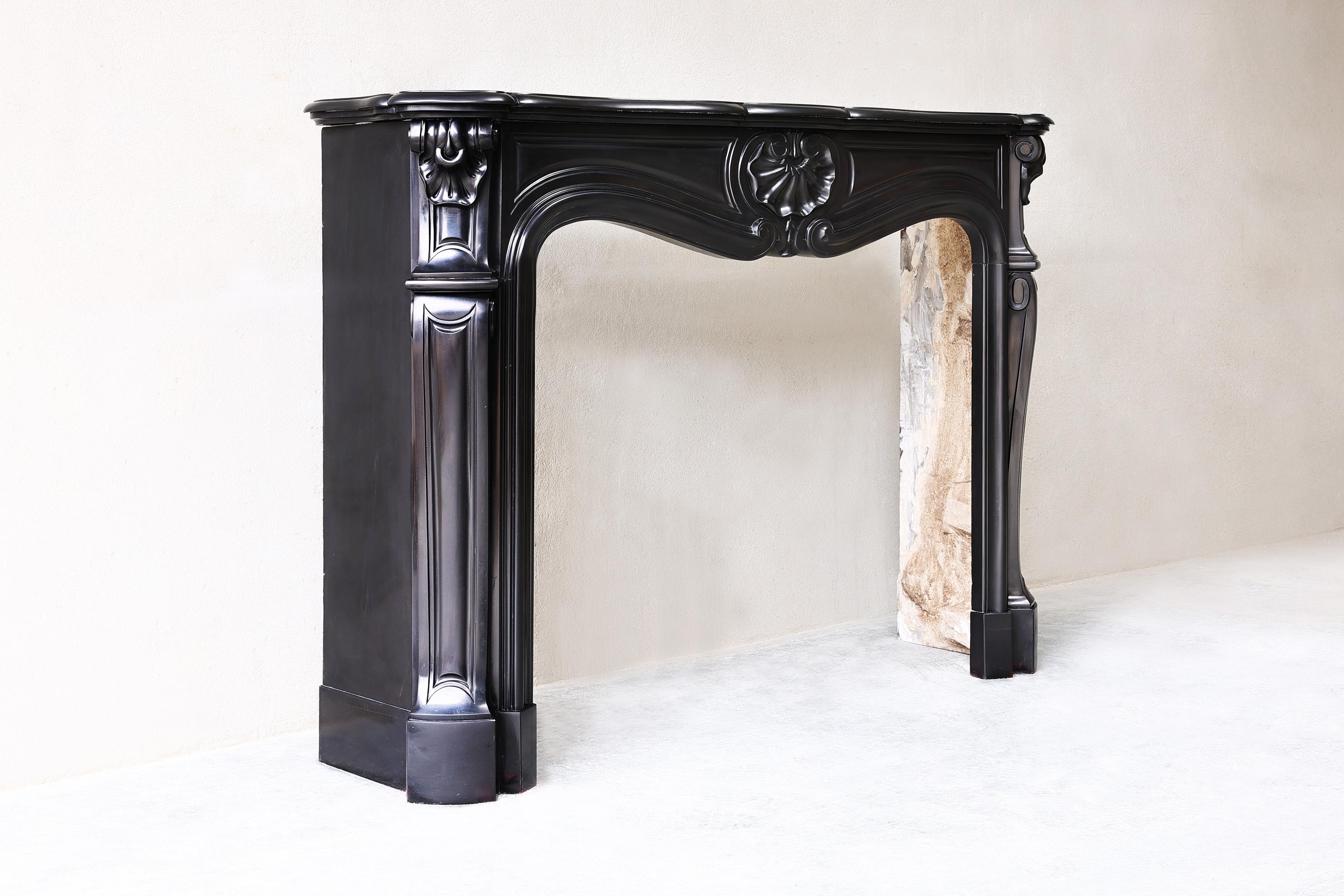 Beautiful antique fireplace of Noir de Mazy marble, also called the 'black gold'! This beautiful fireplace is in the style of Louis XV and dates from the 19th century. A very chic mantle that fits in various interior styles.