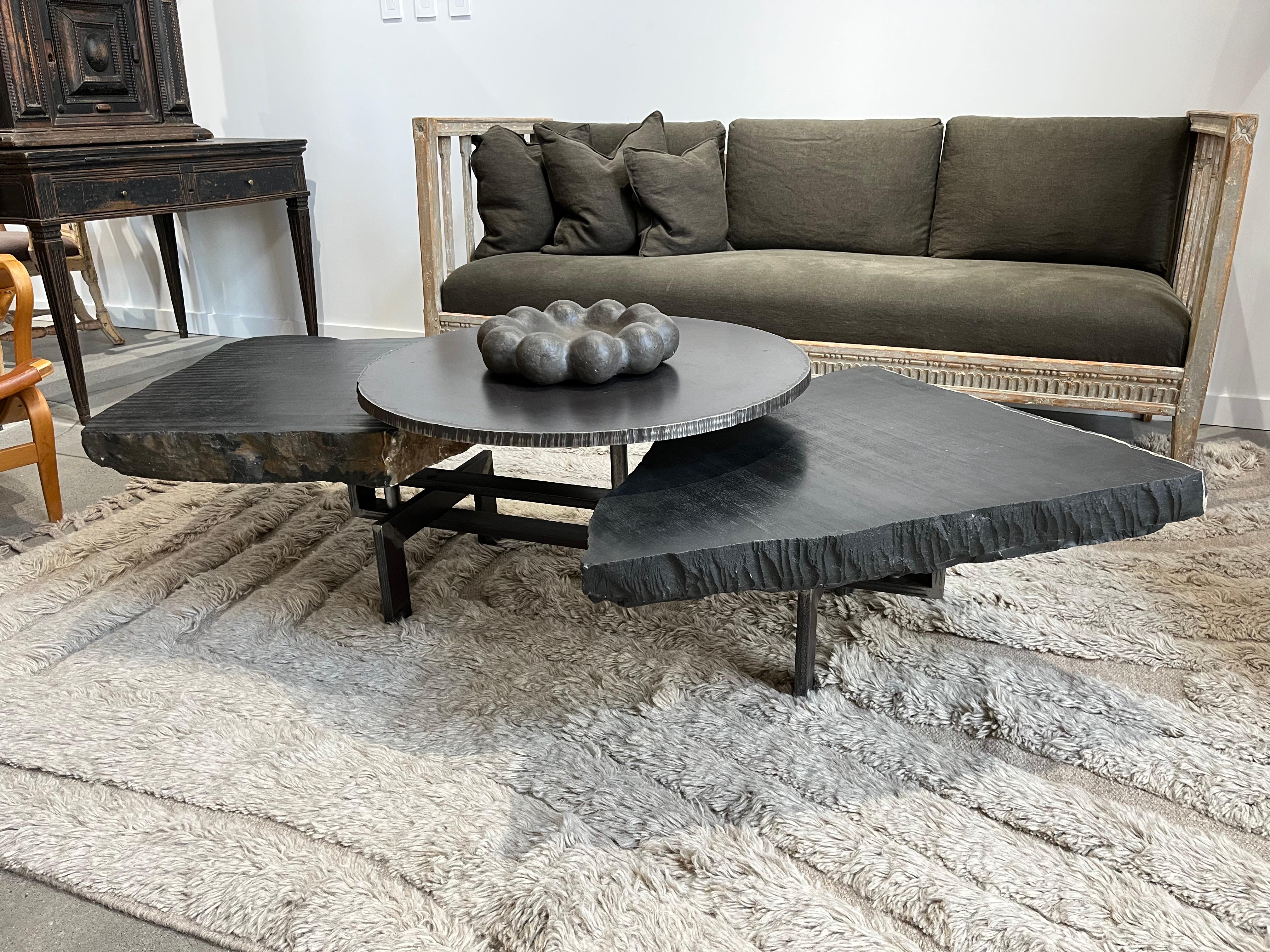 Esta Mesa de centro Noir Trois Assiettes de acero laminado en caliente y mármol negro de Dinant ( Bélgica) puede crecer y encogerse con sólo girar el  bloques de mármol alrededor de sus ejes porque éstos están colocados excéntricamente. Así, pueden
