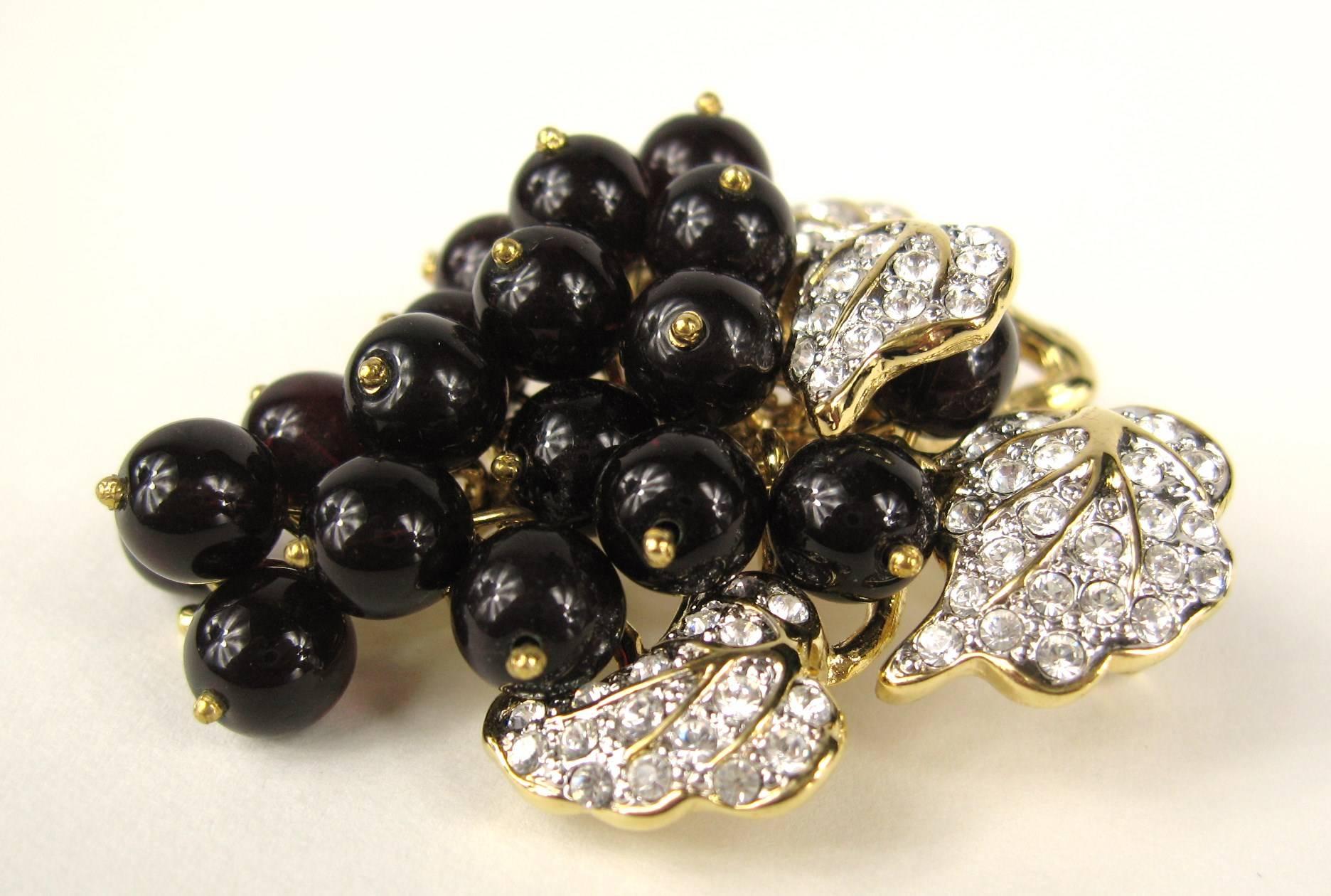 Deep rich glass beads make up the grapes on this vintage Nolan Miller brooch with Pave and prong set crystals are set in the leaves. Measures 2.30 inches Top to bottom  x 2 inches wide. Hallmarked Nolan Miller on the backside. This is out of a