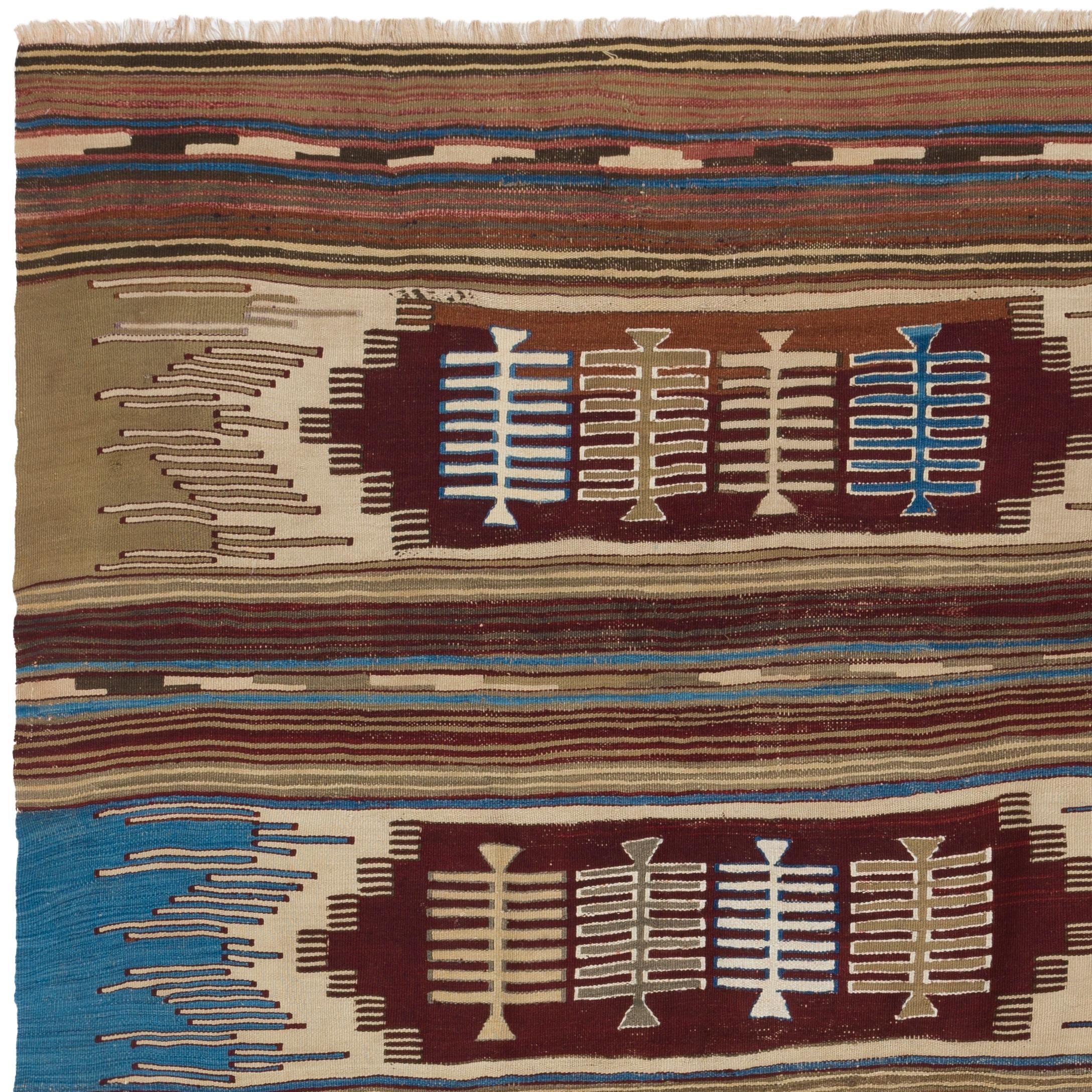 A vintage hand-woven kilim rug from Turkey, made of organic wool, featuring four comb motifs inside four elongated latch hook medallions in four rows across the width of the field in a color palette of burgundy, blue, sand beige, ivory and taupe.