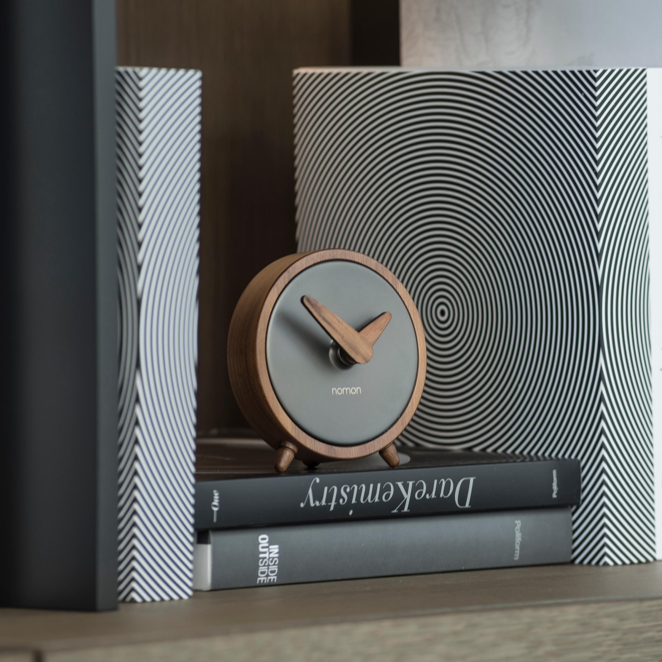 Átomo clocks, whose design reflects creativity with a great sense of refinement, dress the corners of tables and provide light and style.

ø10cm clock with natural walnut wood body, and polished brass or graphite finish central box.

Nomon