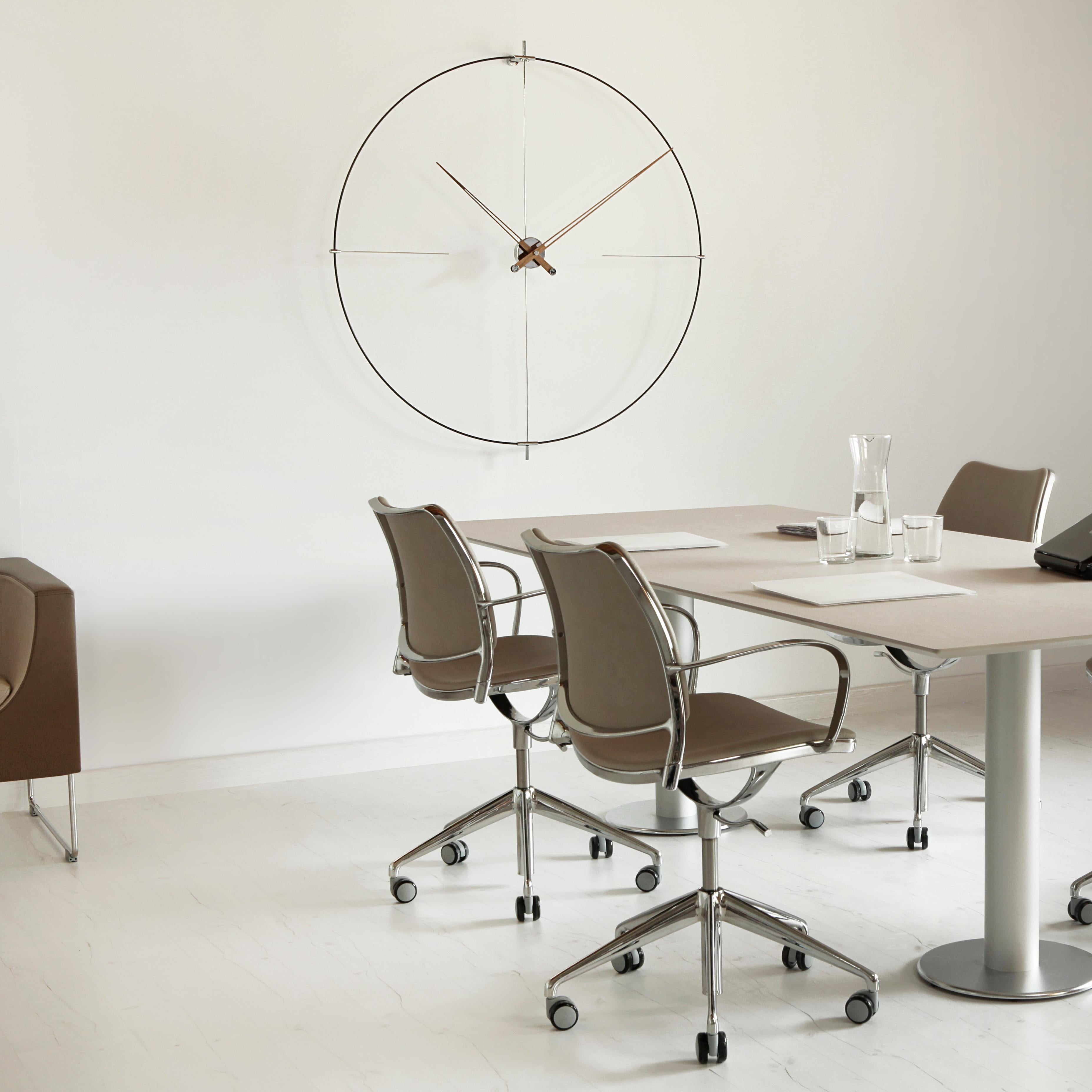 This particular wall clock with lacquered walnut and wooden hands measures 105 cm in diameter and also has parts - such as the hoop and the case - in chromed steel. Its design fits easily in the Nordic and minimalist style. It has an equally