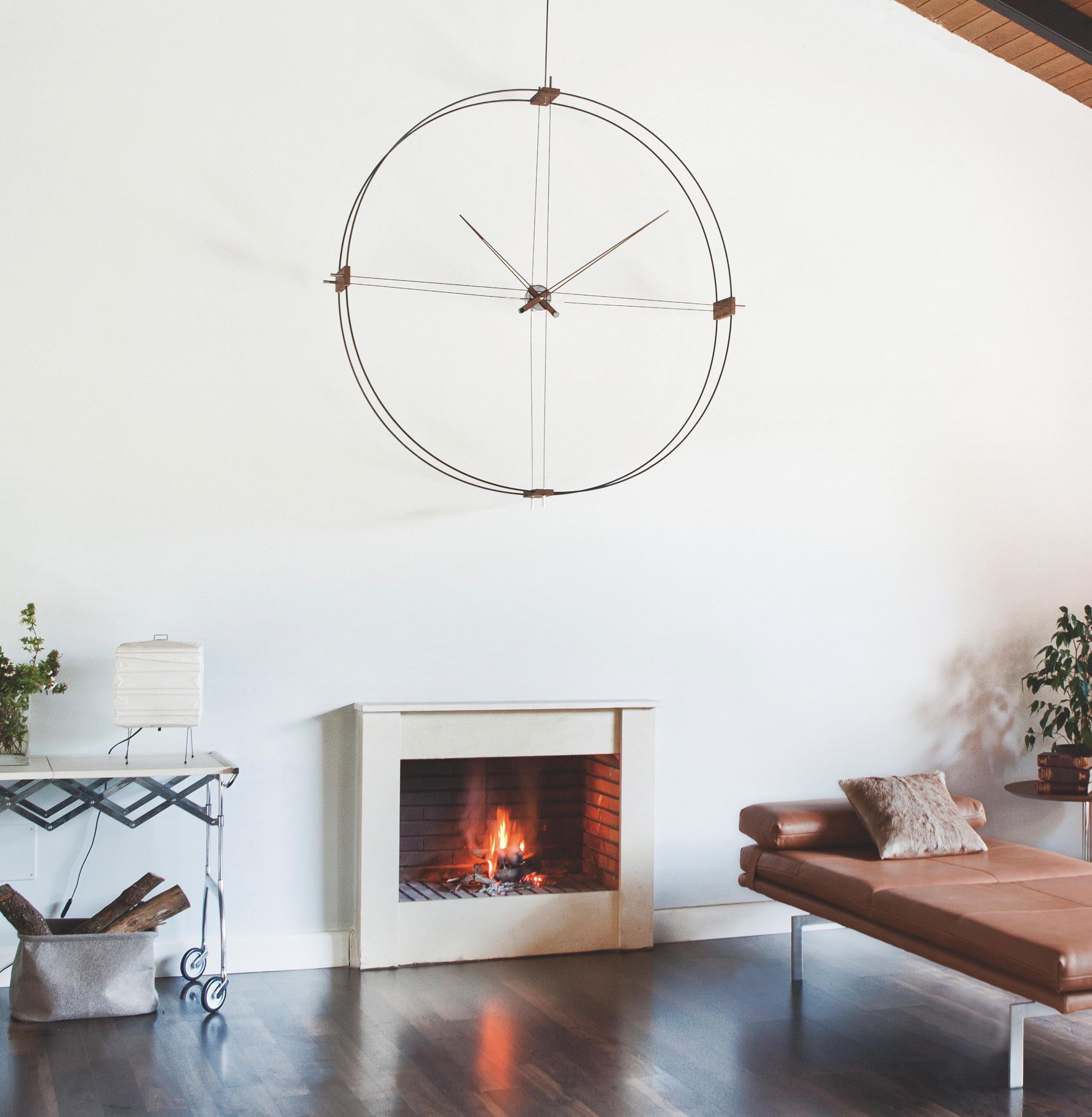 
The largest diameter Nomon clock (130 cm), with double black or white fiberglass ring, metallic details and natural walnut hands. Installation to wall or ceiling.

Clock with black fiberglass which combines polished brass details and central box