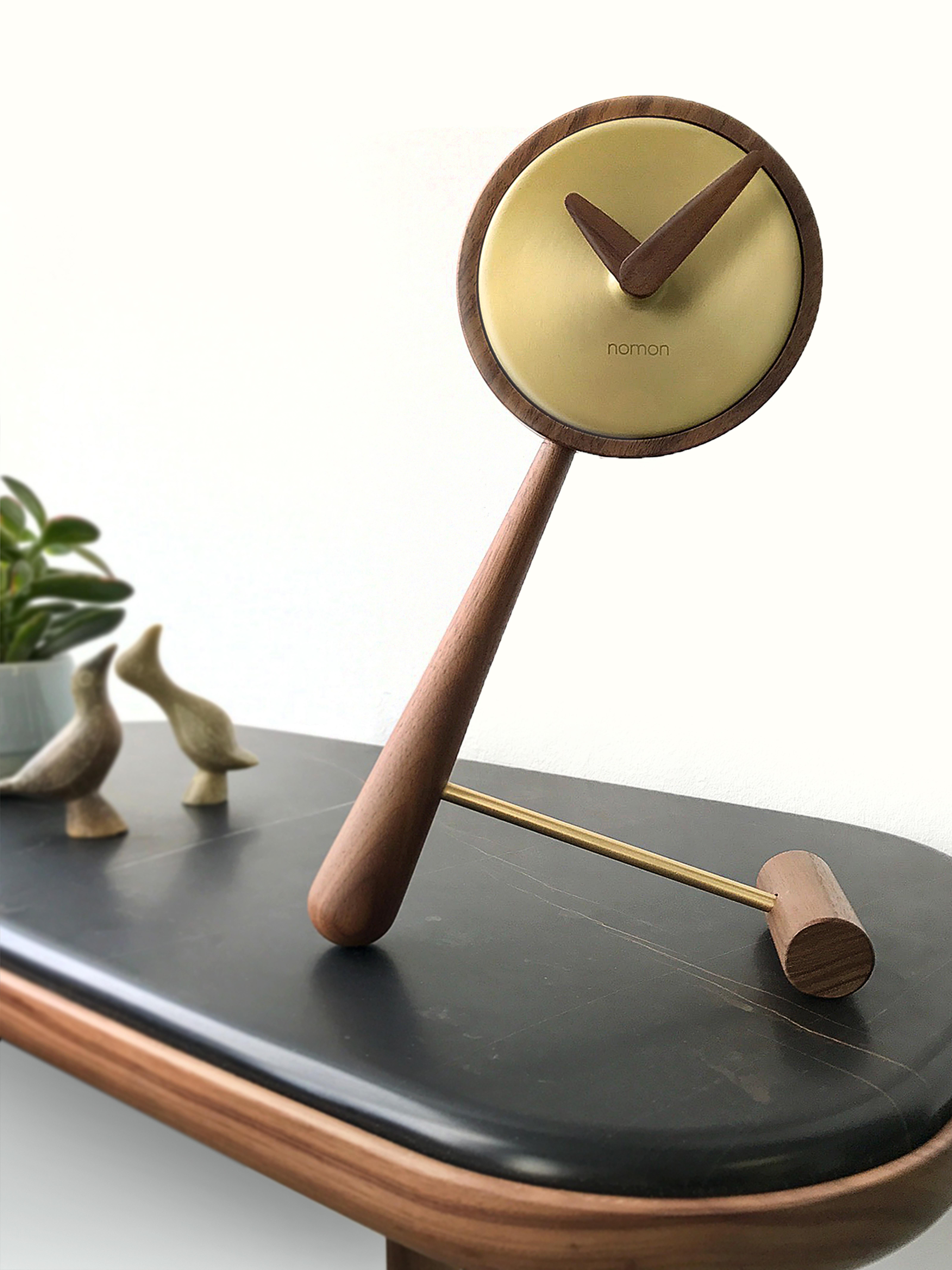 Átomo clocks, whose design reflects creativity with a great sense of refinement, dress the corners of tables and provide light and style.

ø10cm clock with natural walnut wood body, and polished brass or graphite finish central box.

Nomon