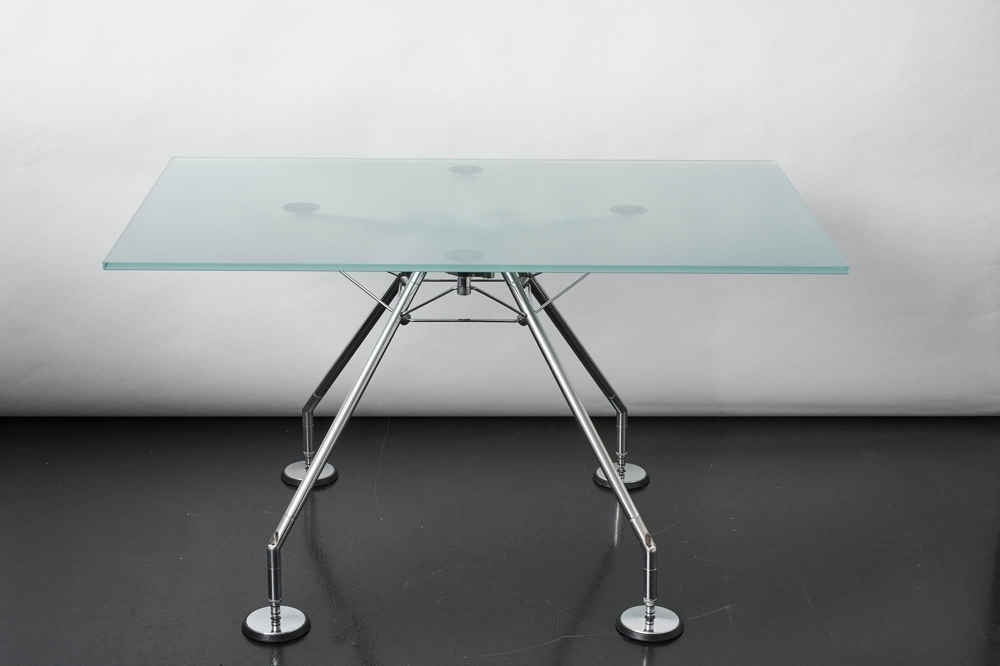 Nomos table with frosted glass top designed by Norman Foster for Tecno, Italy 1987.
The Nomos desk is characterised by its splayed metal legs, angled from a central spine, as if poised for flight.
It surely reminds us of the Lunar landing module