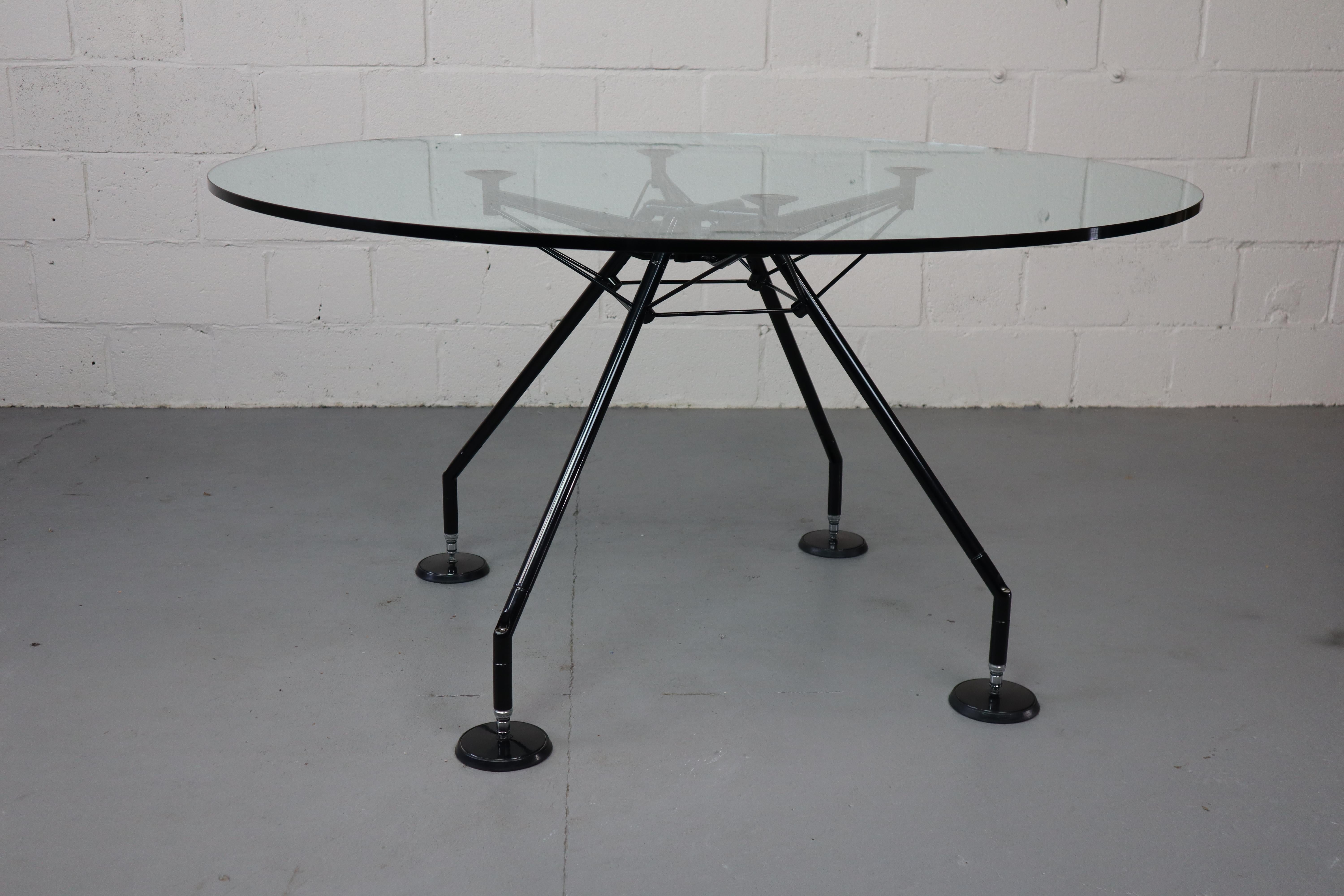Table Nomos par Norman Foster pour Tecno, 1987.
La table a un plateau en verre transparent (verre de sécurité) et une base en métal laqué noir. Hauteur réglable.
Lauréat du prestigieux 