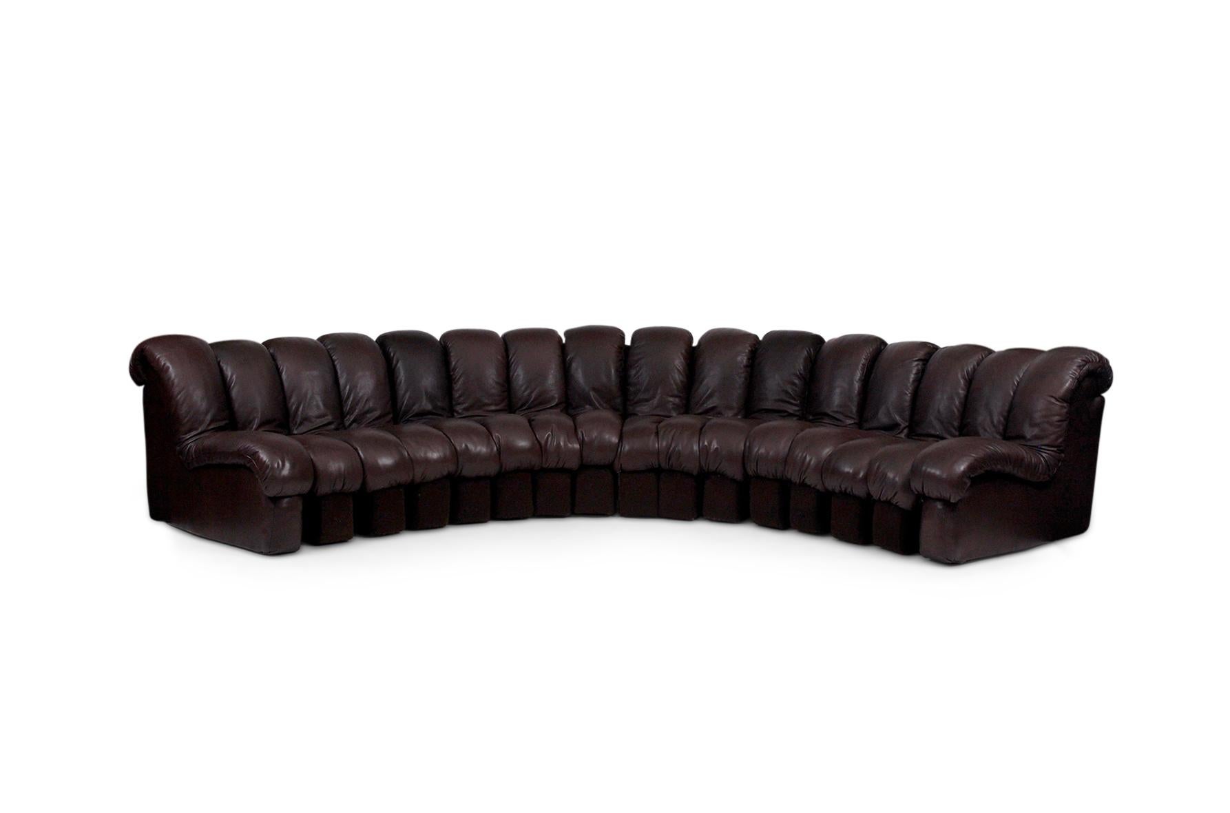 16-Section curved modular sofa in chocolate brown leather. 14 center sections plus two armrests. Each piece is connected by a flexible joint that allows for the shape of the sofa to be manipulated into a variety of curves to fit the specific needs
