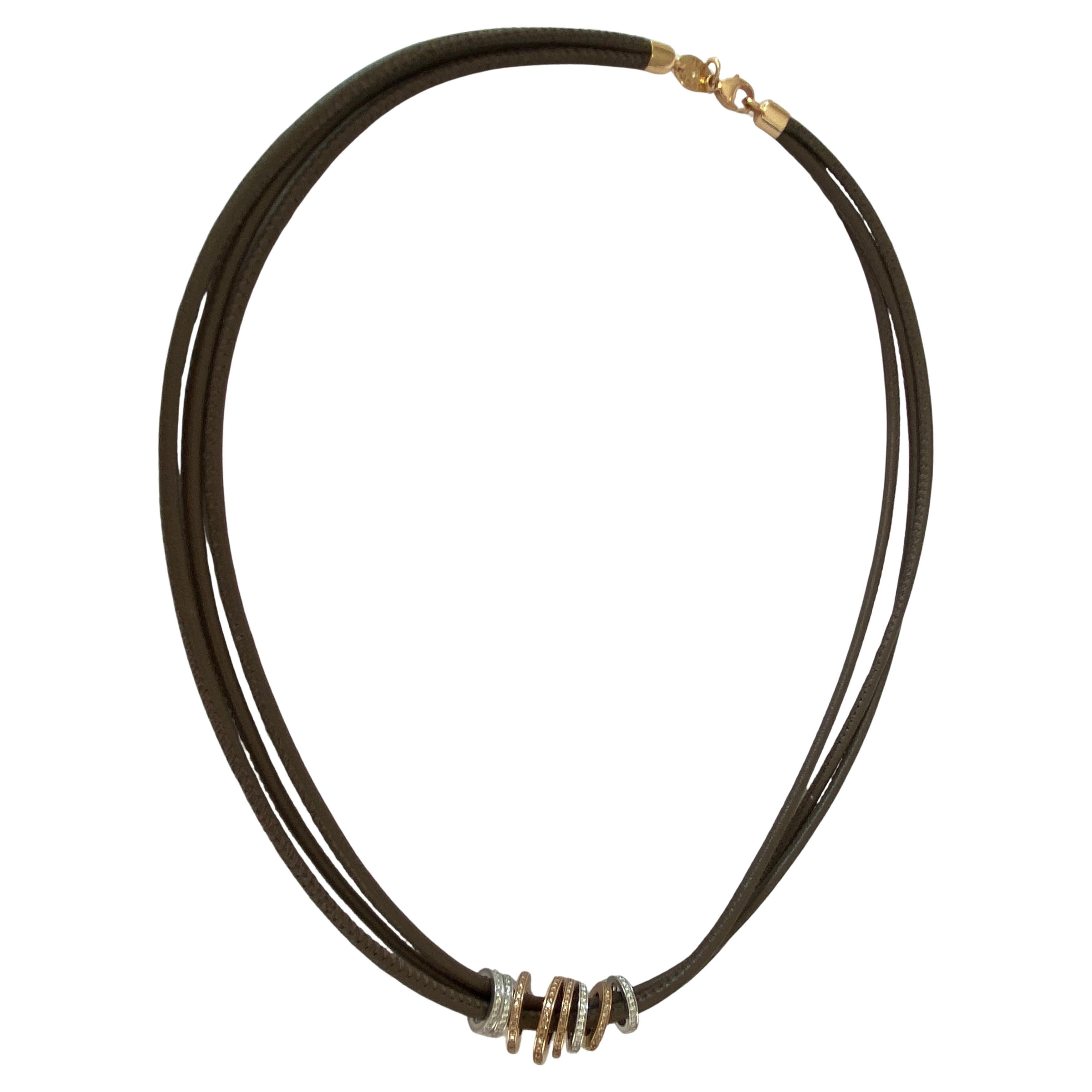 Corde in nappa in ottime condizioni con ciondolo in oro bianco e rosa 18 kt con pavé di diamanti bianchi e marroni. Il ciondolo è composto da anelli in oro bianco e rosa 18 kt.  con il bianco  diamanti 0,63 crt G/VS  e diamante marrone  0,77 crt/VS.