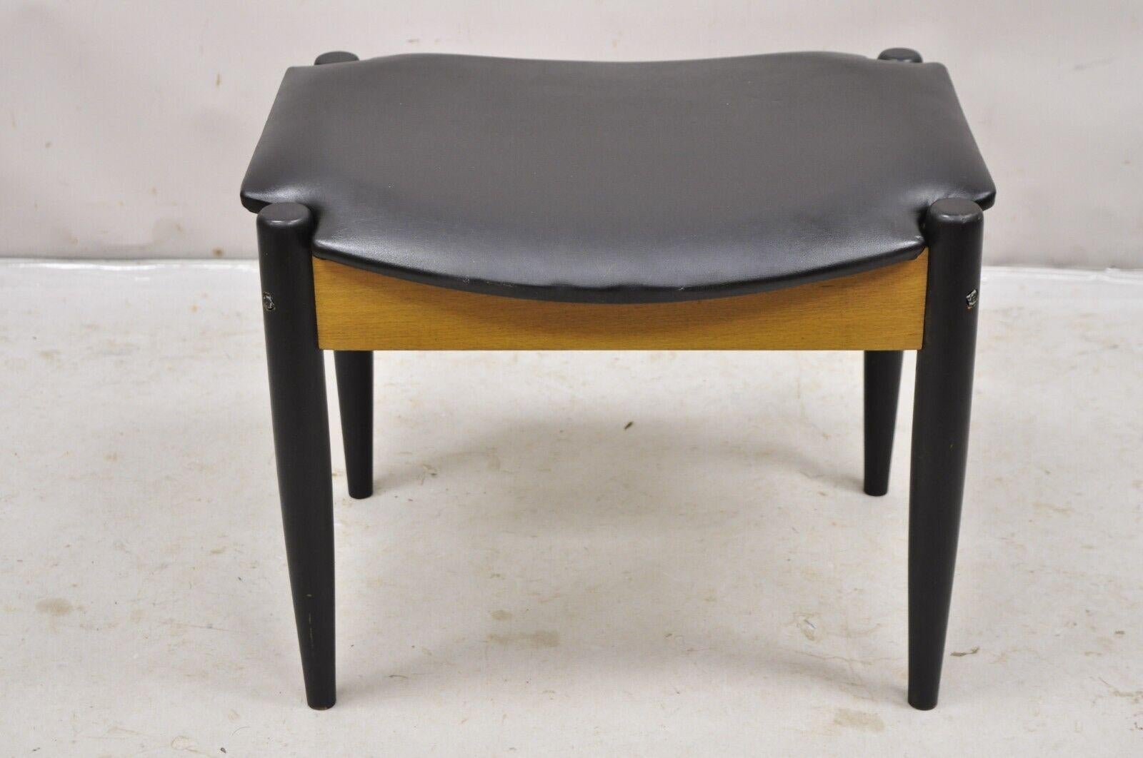 Norco Mid Century Modern Sculpted Footstool Ottoman with Tapered Legs and Black Vinyl Seat. Circa Mid 20th Century.
Measurements: 16