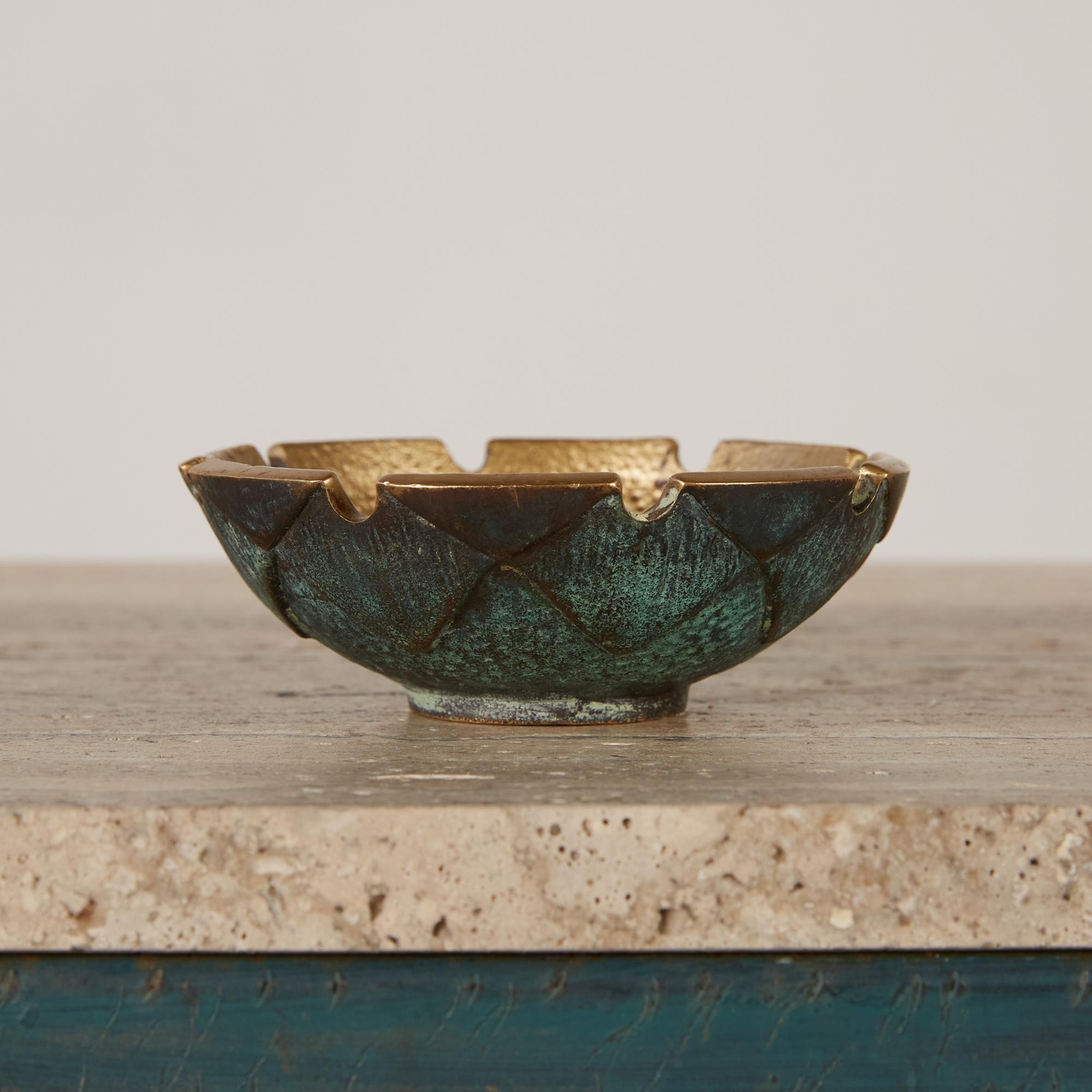 A solid bronze round ashtray with object resting details all around. It has a gilt bronze pebbled interior and beautiful deep rich verdigris finish on the underside. It is made in Israel by Nordia and is marked on the underside.

Dimensions: 4.75