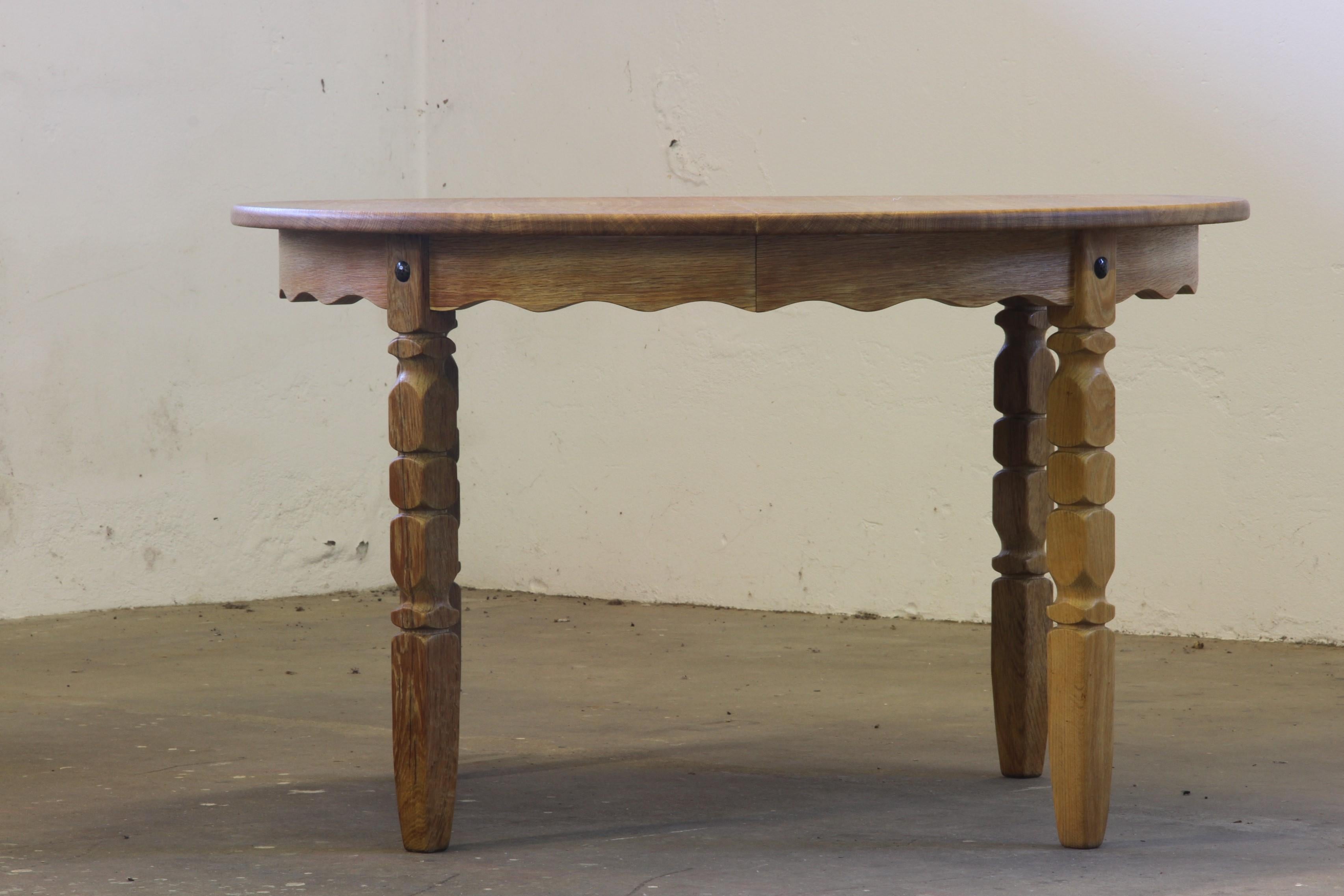 This vintage mid-century oak dining table embodies Henning Kjærnulf’s bold brutalist aesthetic and refined Danish craftsmanship. Its intricate leg carvings complement the table's rounded shape, delivering a perfect blend of Nordic design and