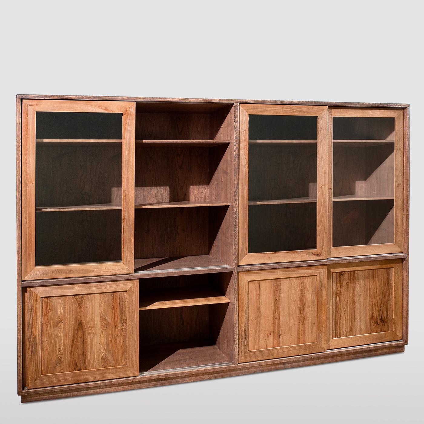 Refined cabinetry techniques meet elegant modern details in this clean-lined bookcase handcrafted from ash and solid walnut. The external shell is marked by a melange hue, while the interior and front doors boast a natural finish. Resting on a
