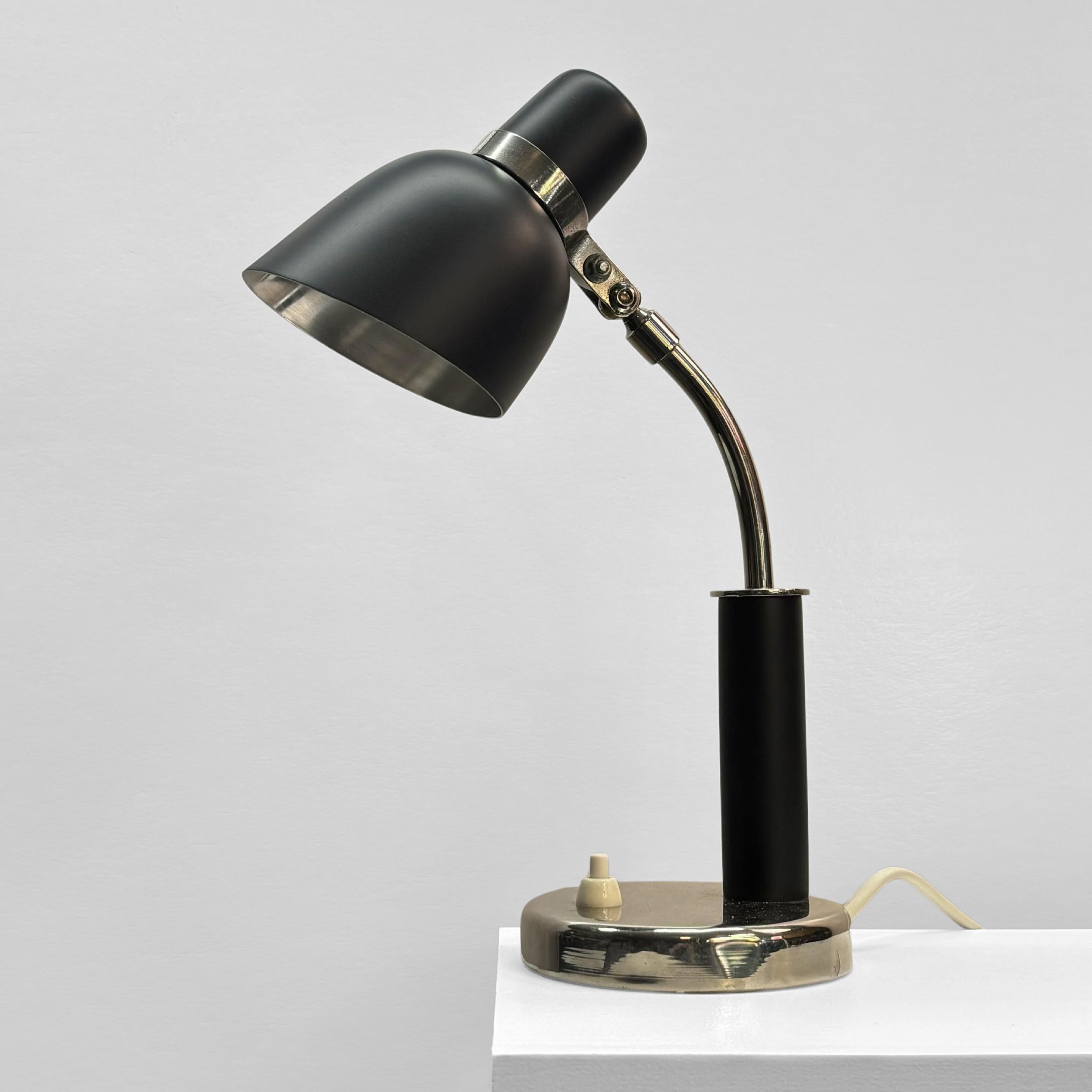 Petite lampe de table, faisant également office d'applique, produite par le département éclairage du grand magasin suédois Nordiska Kompaniet dans les années 1930, probablement conçue par Erik Tidstrand. Fabriqué en acier et en métal chromé avec des