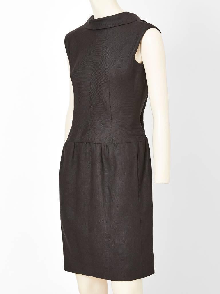 Norman Norell, Moygashel linen, black, day dress, having a fitted bodice, slightly capped sleeve, a rounded banded  neckline, dropped waist with gathering at the hip with hidden pockets.  Bodice is fitted. Back of the dress has a pointed collar and