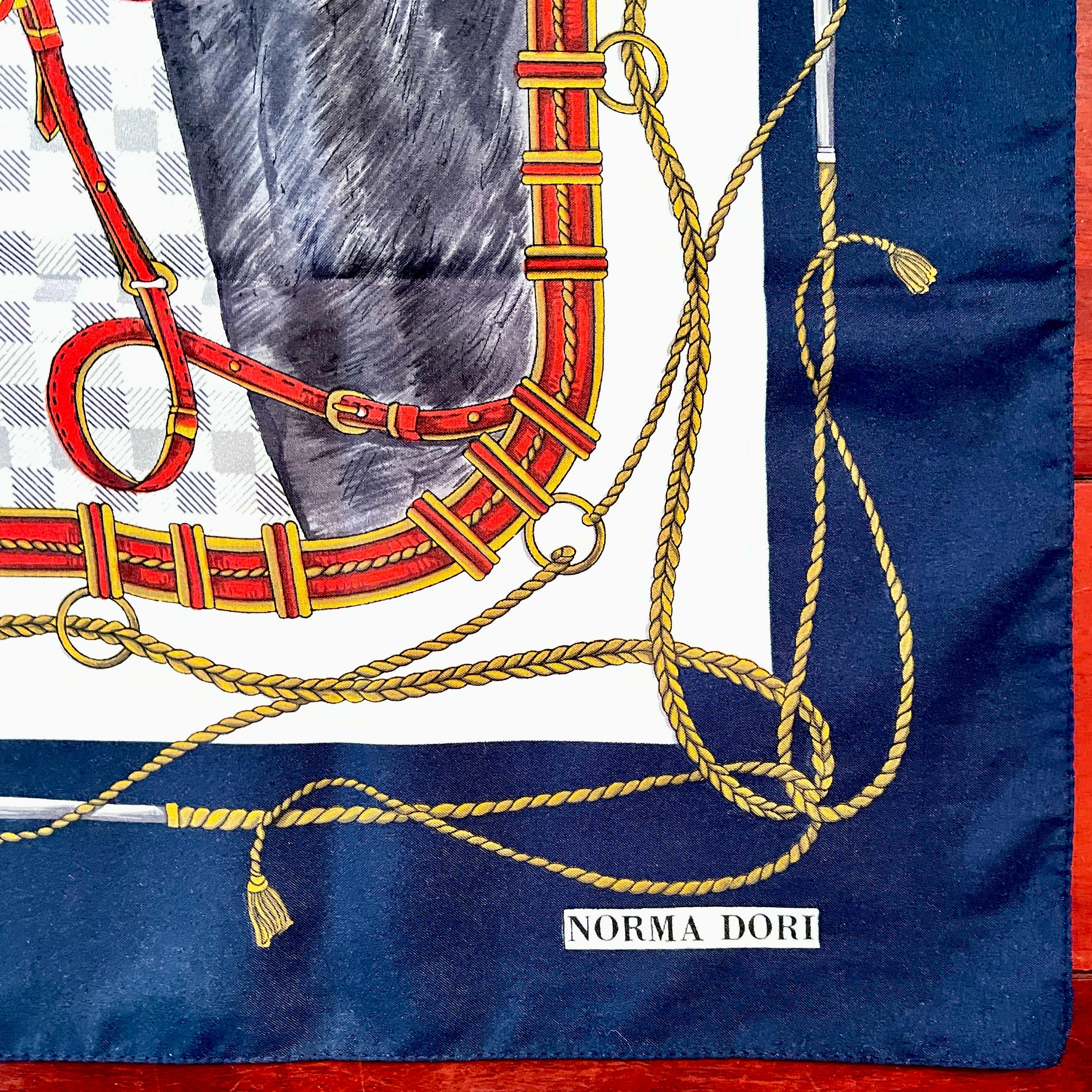 Un foulard vintage à thème équestre de la créatrice londonienne Norma Dori, vers la fin du 20e siècle.

Représentant la tête d'un cheval noir portant une bride rouge. L'arrière-plan présente des motifs équestres, notamment un fer à cheval, des rênes