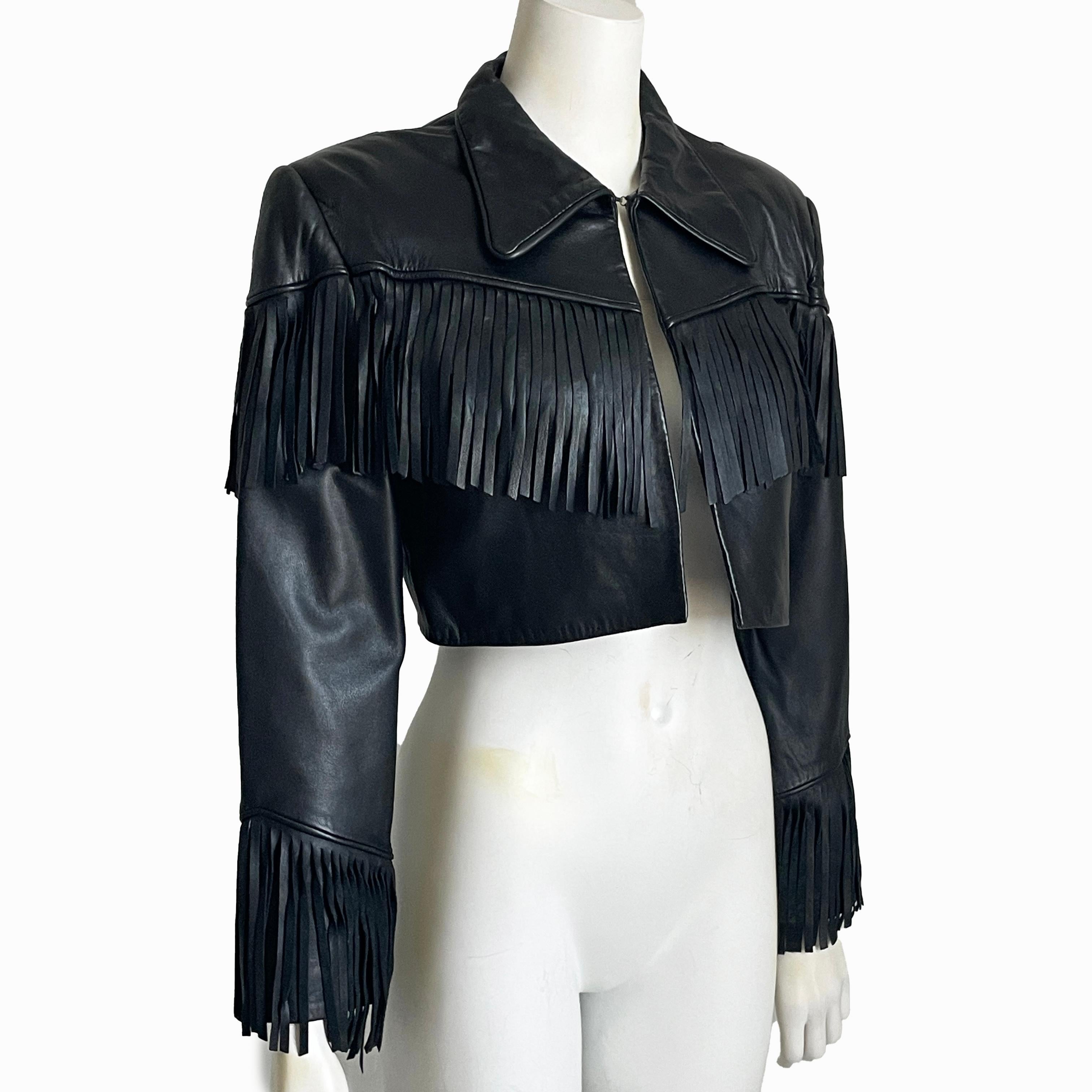 Preowned, vintage Norma Kamali cropped black leather jacket with fringe, likely made in the early 90s.  Made from supple lambskin, it's lined in black satin and fastens with a single hook/eye closure at the collar.

Definitely rocker chic vibes with