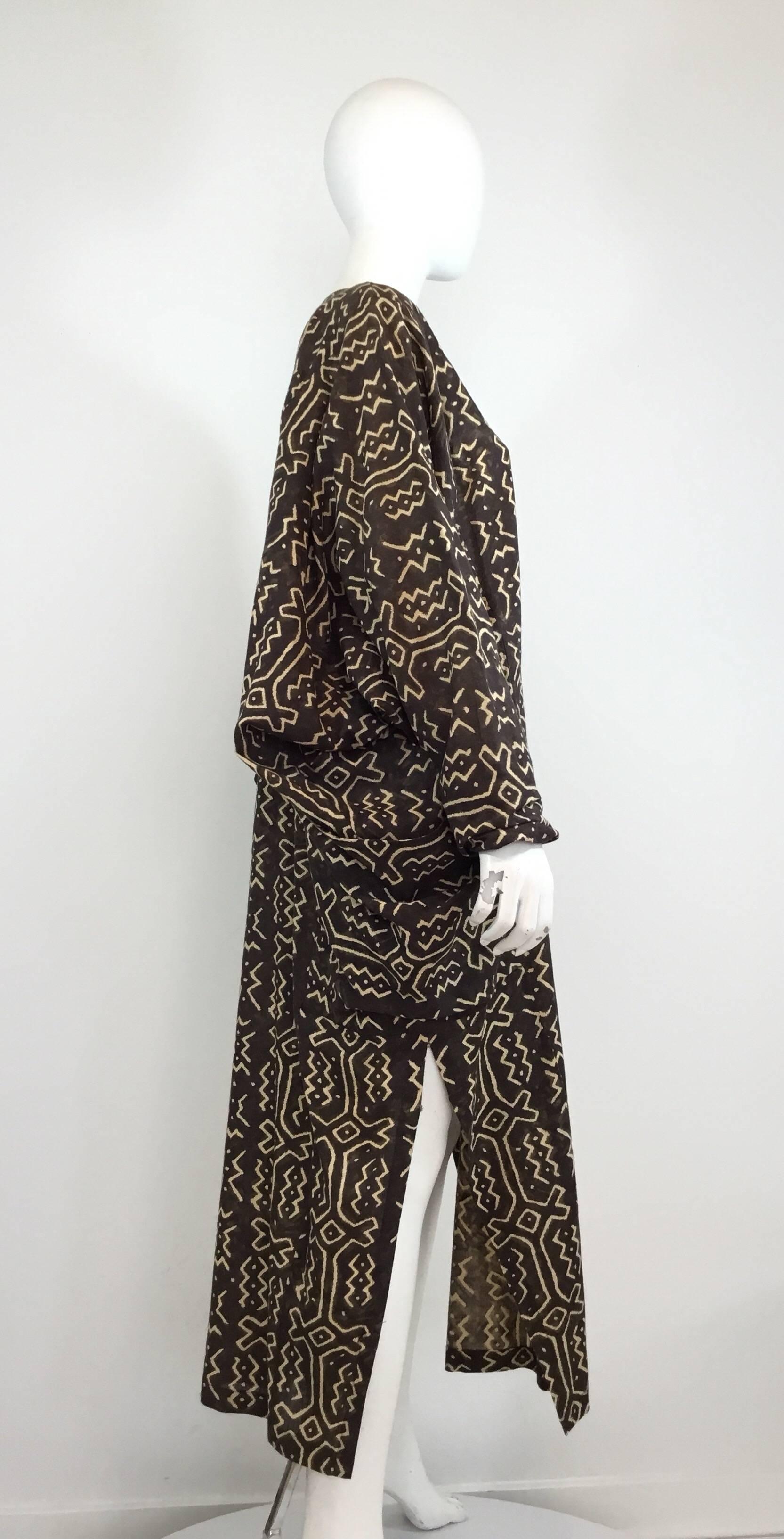 Norma Kamali caftan featured in brown and beige cotton with a tribal print throughout. Caftan has dramatic, oversized dolman sleeves and large pouch pockets at the hips. Labeled size M. Measurements: bust 66'', sleeves 32'', waist 68'', length