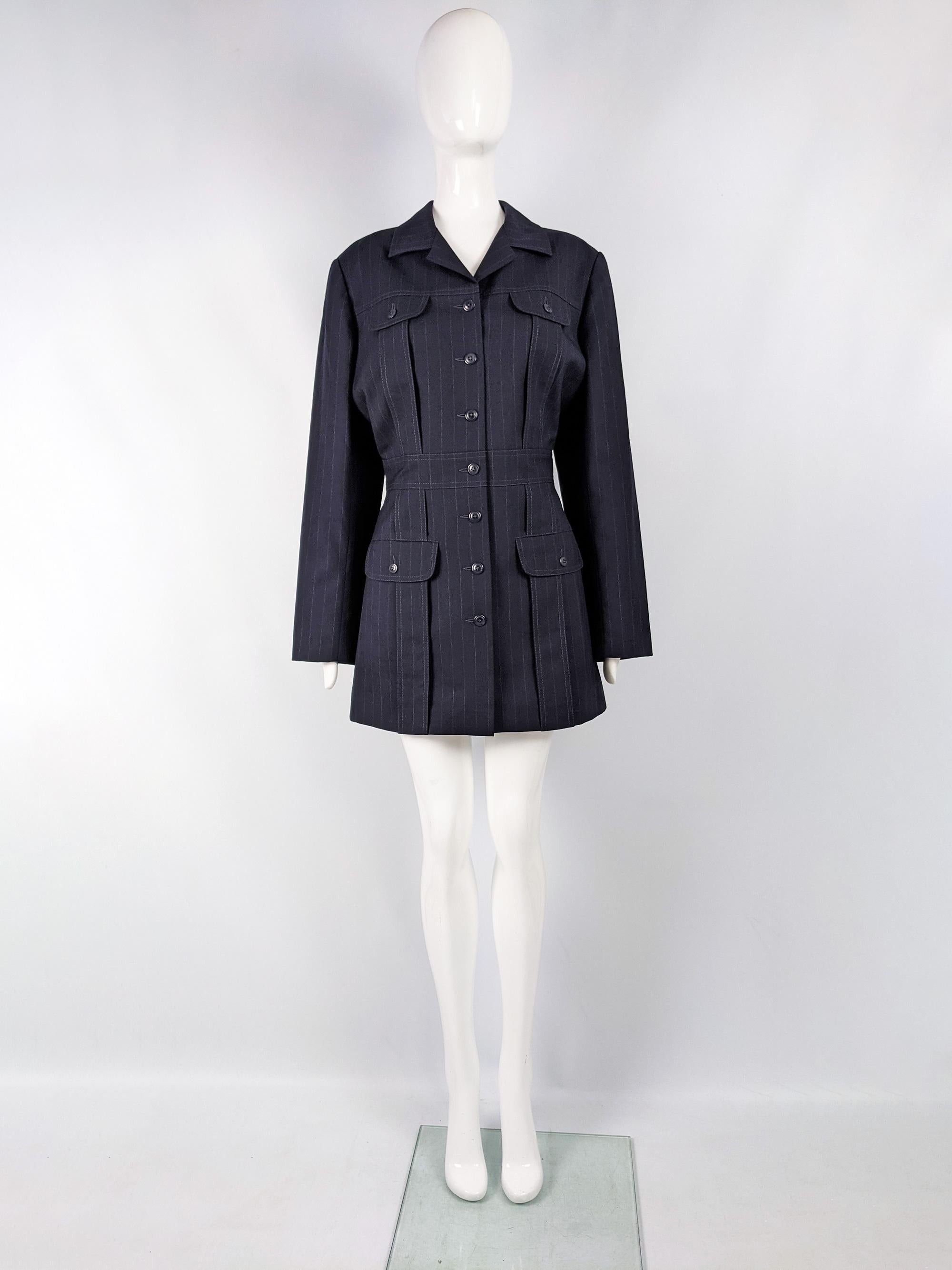 An incredibly chic vintage women's blazer jacket from the 80s by luxury American fashion designer, Norma Kamali. In a dark navy wool suiting fabric with a pinstripe detail throughout. This would also look great worn as a dress. IT has a nipped waist