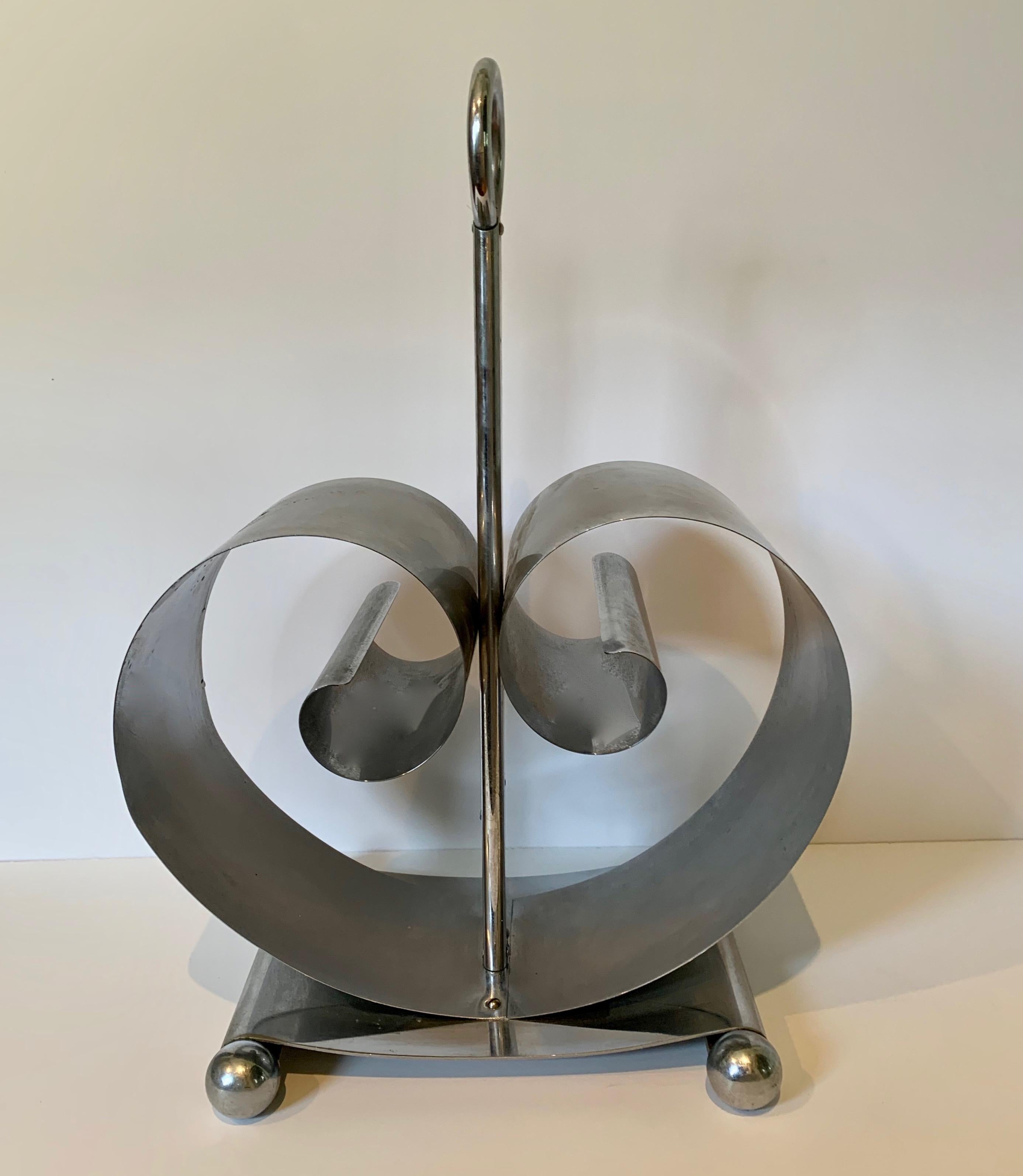 Norman Bel Geddes Chrome magazine rack, the curled sides expand depending on the number of magazines or books within each side.

A wonderful for addition to midcentury, modern and especially Art Deco Design - elegant and sophisticated design.