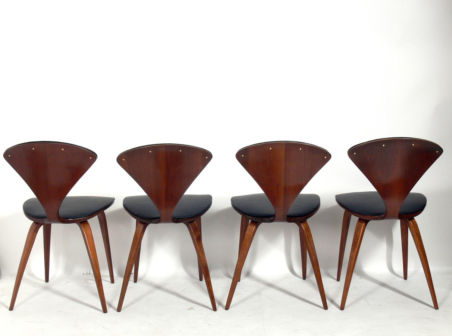 Set of eight sculptural dining chairs, designed by Norman Cherner for Plycraft, American, circa 1950s. They have all been refinished and reupholstered in black vinyl. They measure: 31.25