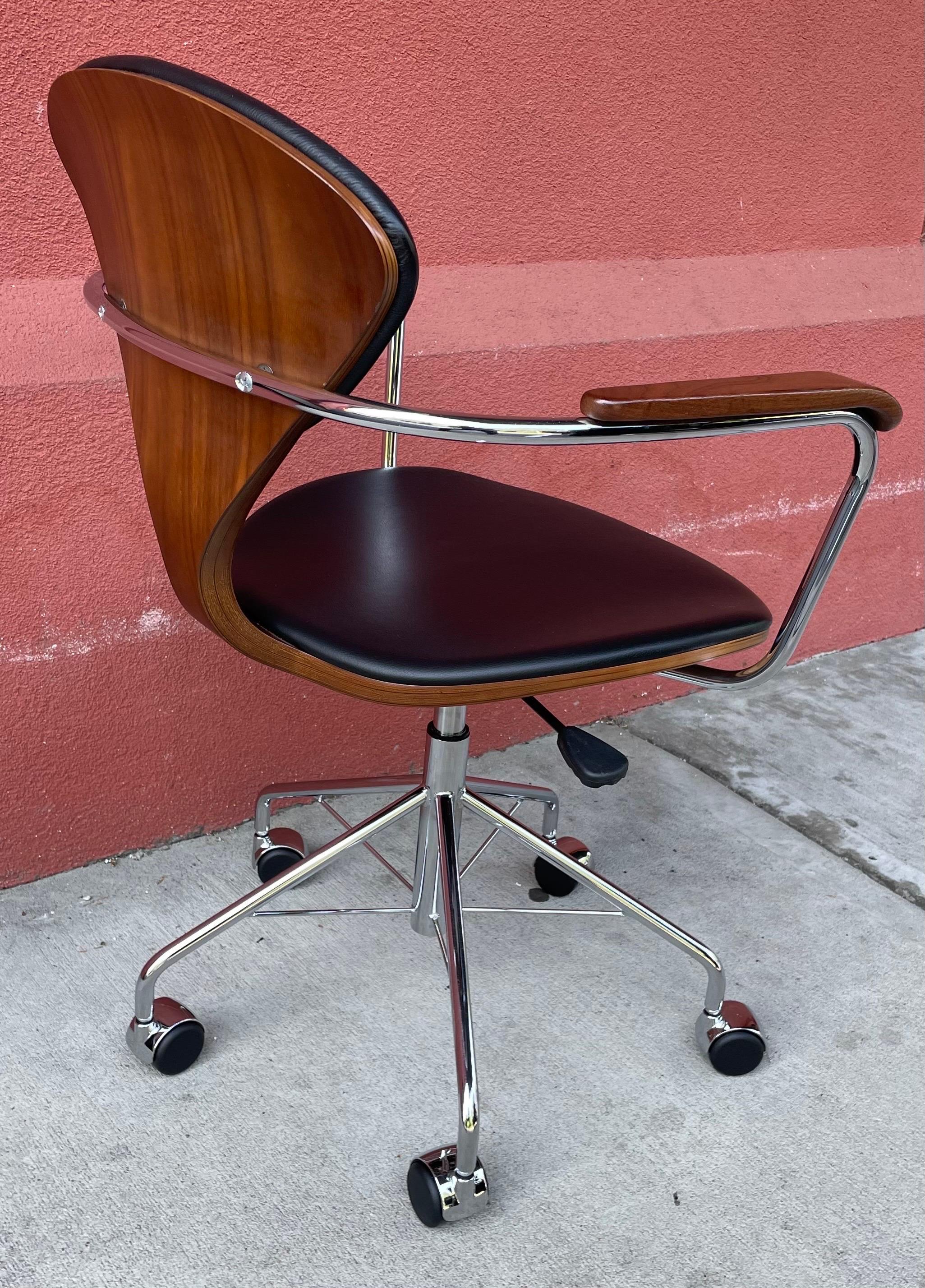 Beautiful Norman Cherner task chair in walnut with arm rests, chrome base, black leather seat and back rest.