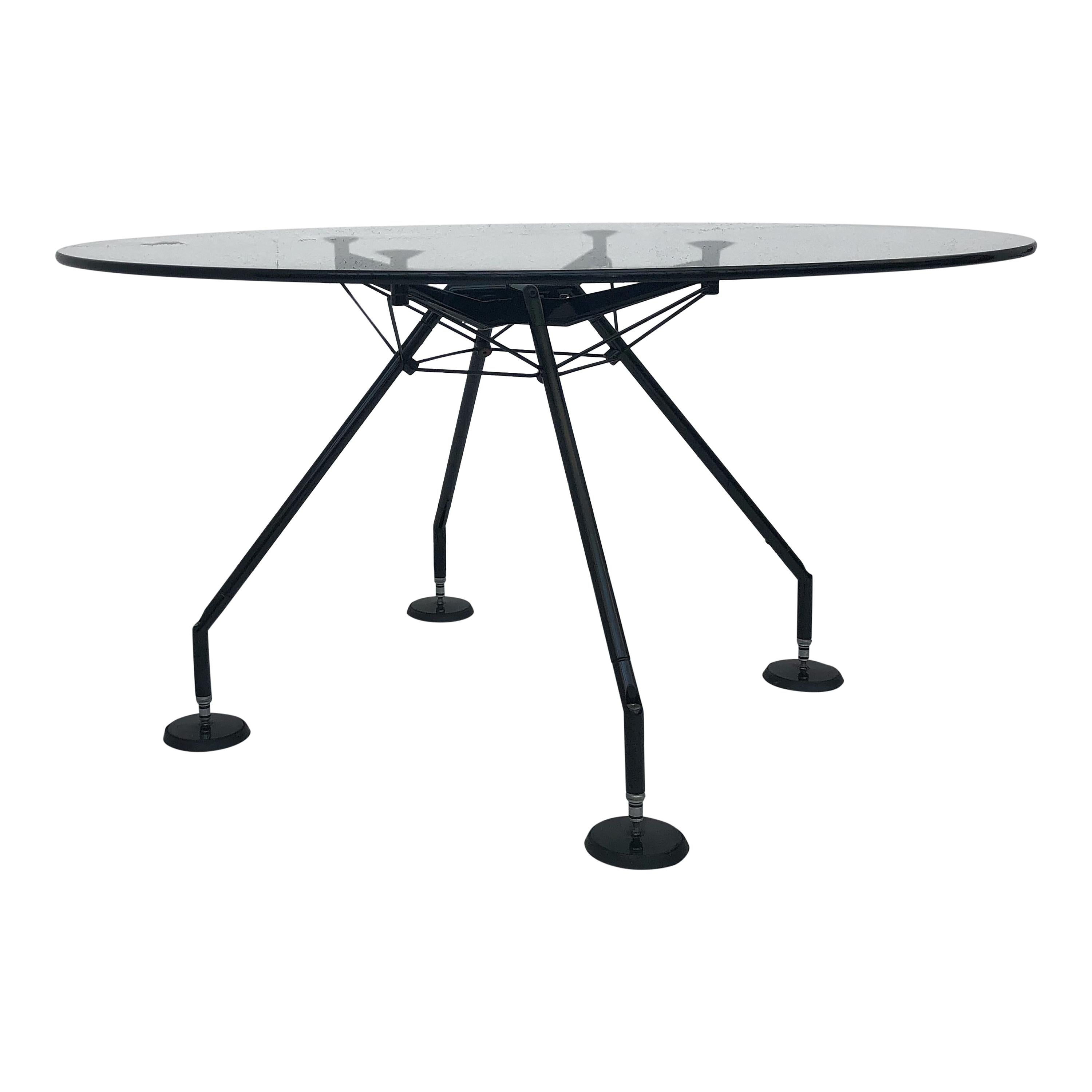 Runder Nomos-Tisch, entworfen 1986 von  Sir Norman Foster und 1988 von Tecno produziert. Seine glänzende Glasplatte, die von einem schwarz lackierten Aluminiumgestell getragen wird, bietet eine unvergleichliche Ästhetik, die auffällig und