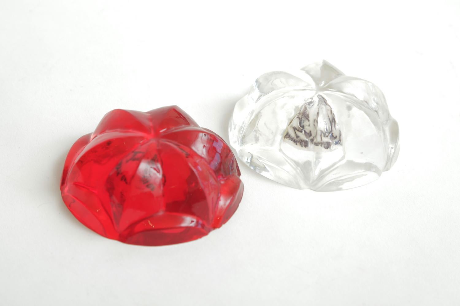 This wonderful pair of Norman Mercer Lucite paperweights are red and clear with a semi flower design. They make a great desk accessory as a sculptural entity. Norman Mercer worked in lucite after studying and having a career in engineering. He was