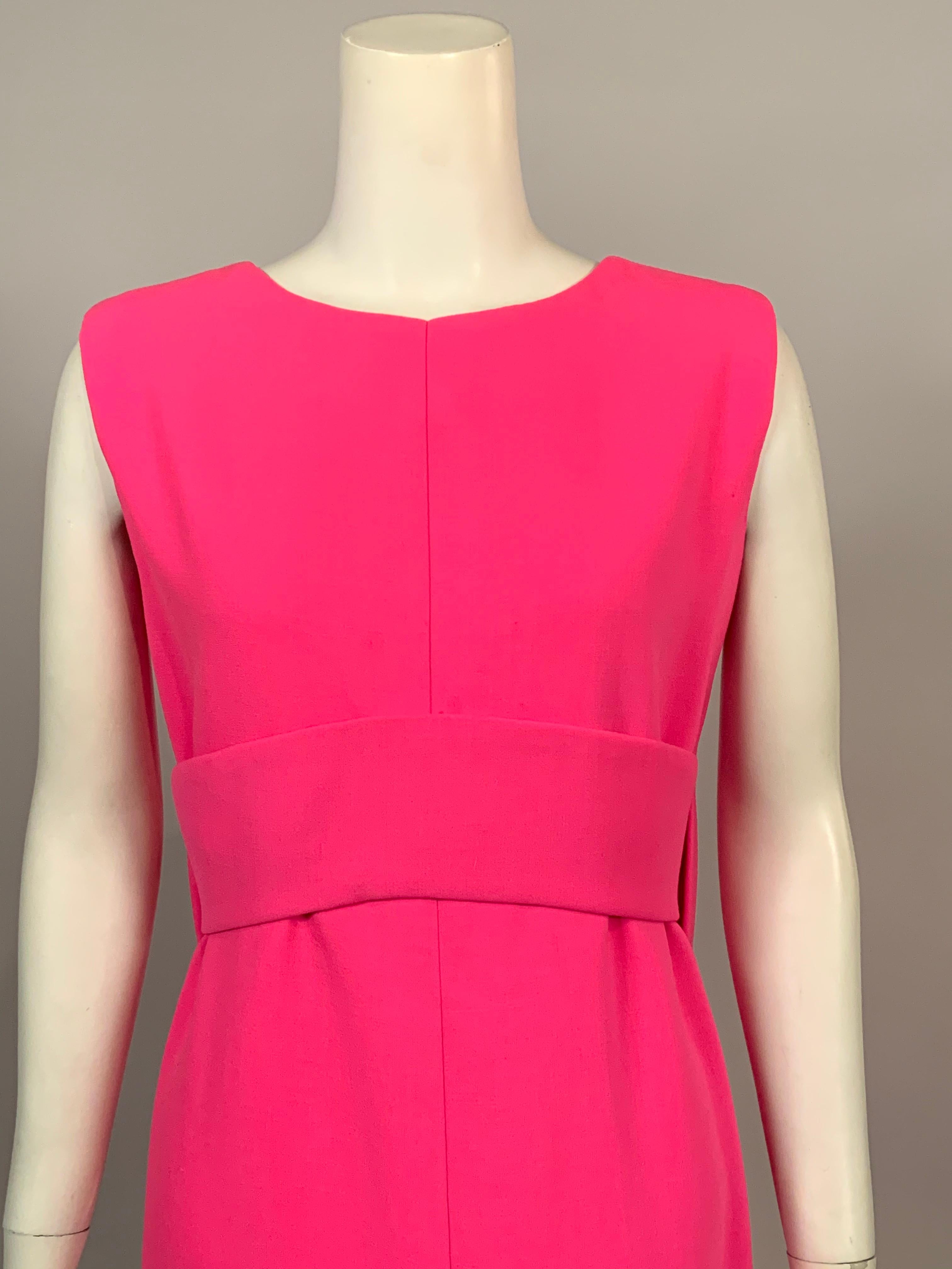 This classic bright pink wool crepe evening dress from Norman Norell is as stylish today as it was in the 1960's, and it is a perfect backdrop for your favorite jewelry. The sleeveless dress has a round neckline and an Empire waist created by a wide
