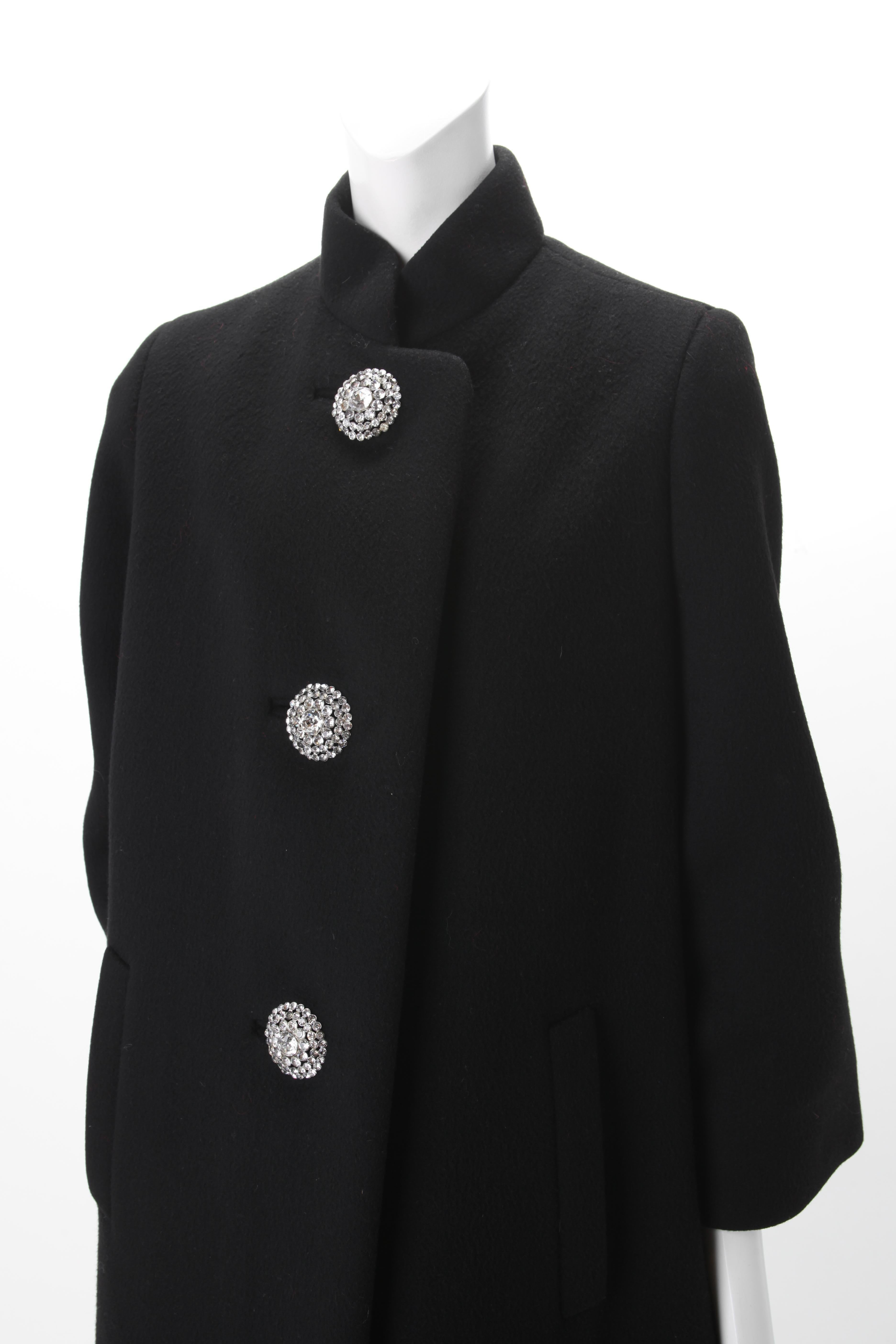 Norman Norell Couture Black Wool Coat with Rhinestone Encrusted Buttons, c.1960s
A-Line Norman Norell Couture Black Wool Coat with Mandarin collar and welt bound pockets at hip. Featuring three large Rhinestone encrusted buttons at center