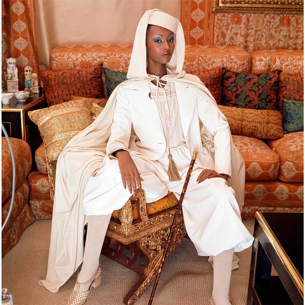 Iman posa con un traje monocromo de Valentino, capa y tocado rodeada de almohadas ornamentadas para Vogue Italia en marzo de 1976. Musa de los diseñadores Gianni Versace, Thierry Mugler, Calvin Klein, Donna Karan e Yves Saint Laurent, también estuvo