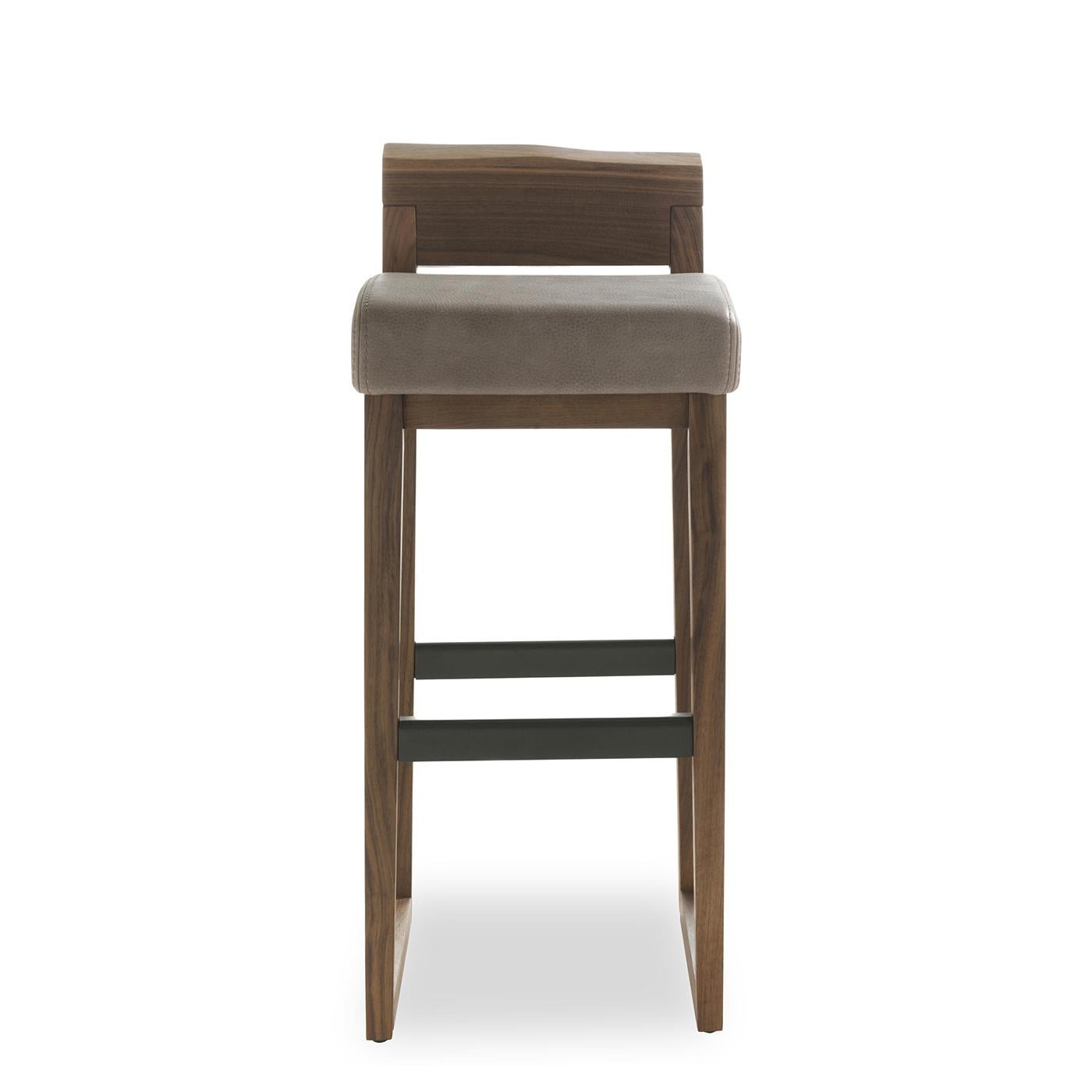 Stool Norman with solid walnut wood structure,
handcrafted wood treated with wax with natural
pine extracts. With upholstered seat covered with
high quality Italian genuine leather D3 with
exposed stitching. With raw iron footrest lacquered
in iron